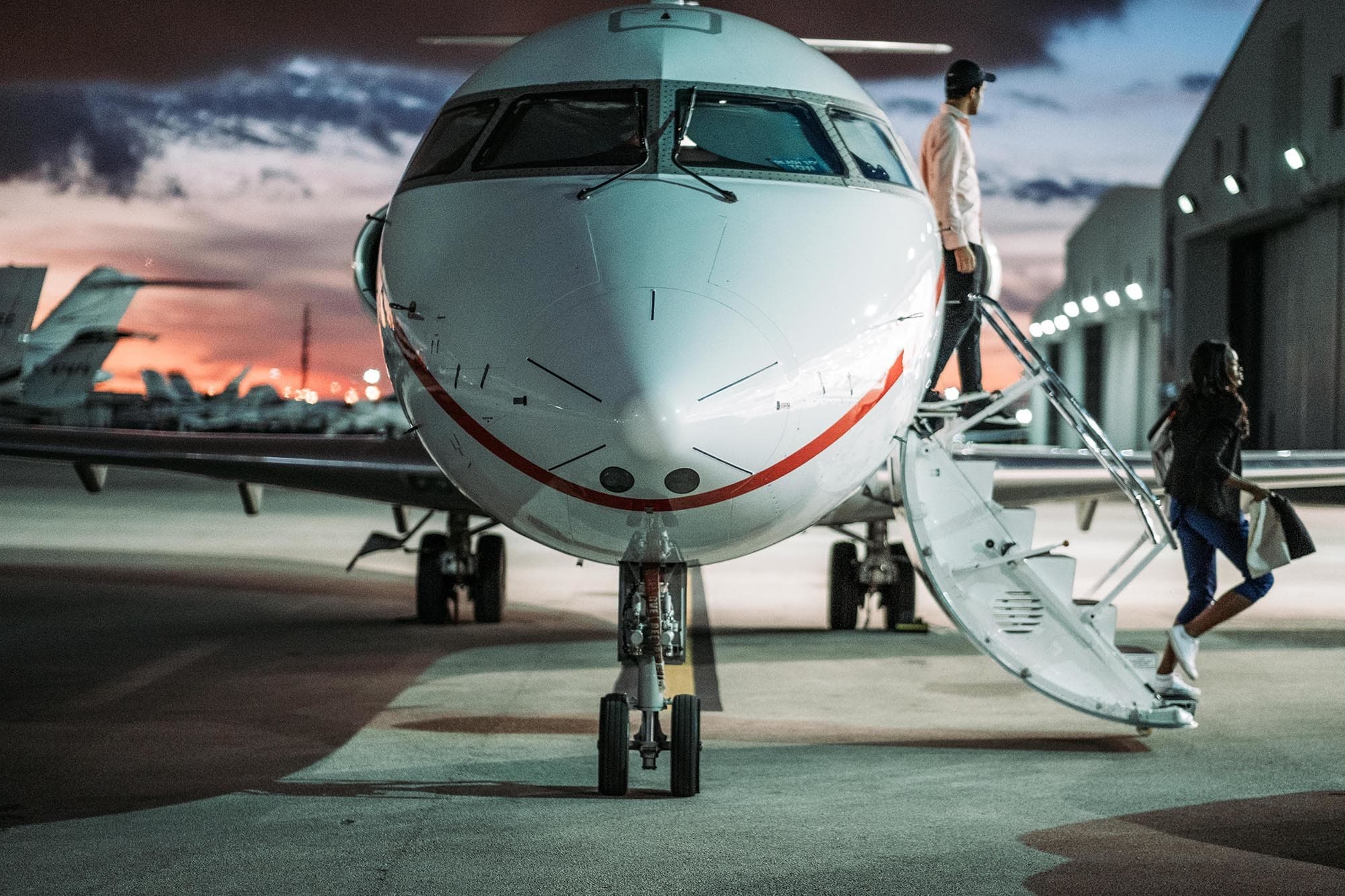 Passengers boarding a private jet on the tarmac at dusk