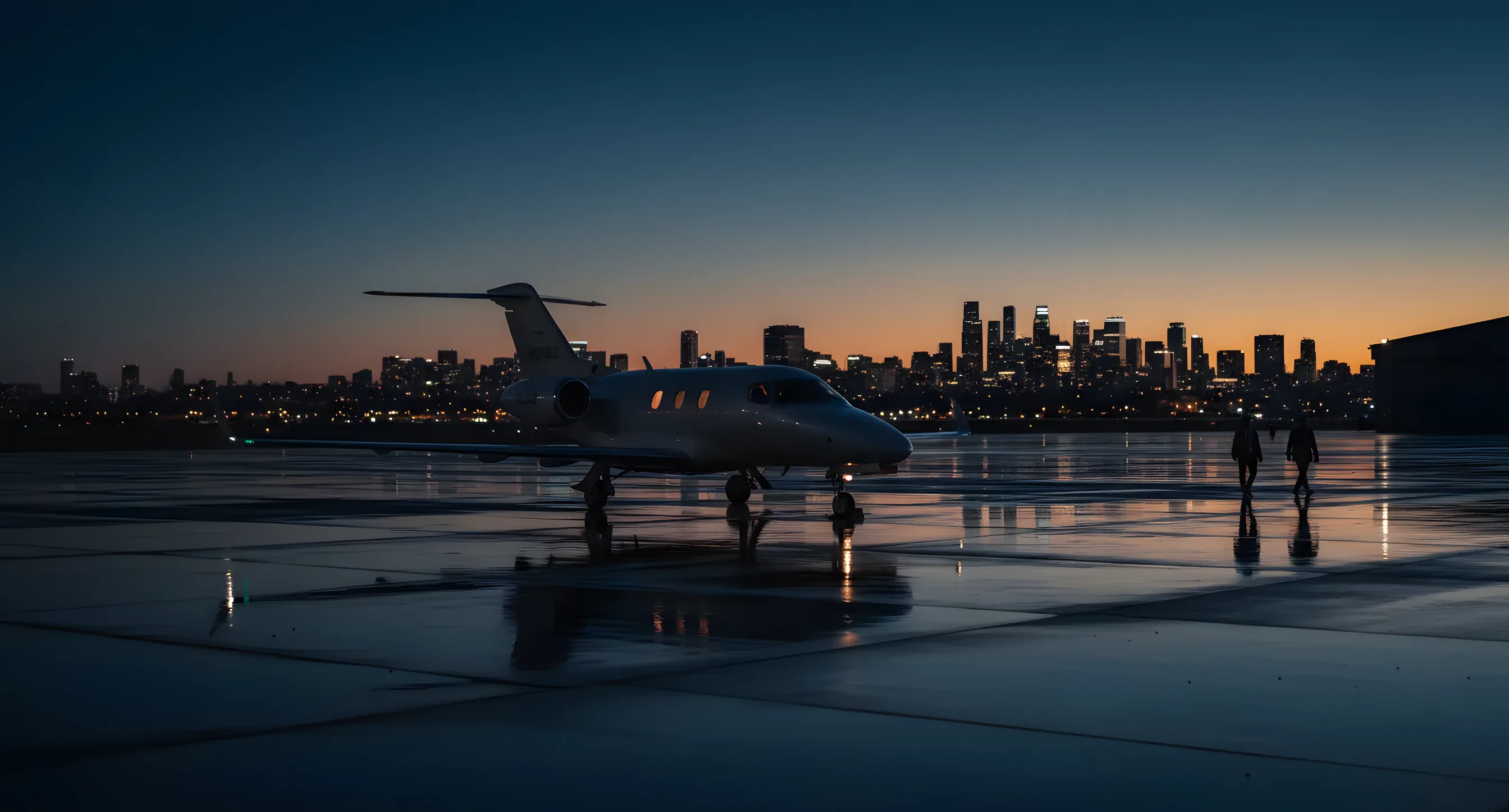A private jet on an airport tarmac at dusk with a city skyline in the distance.
