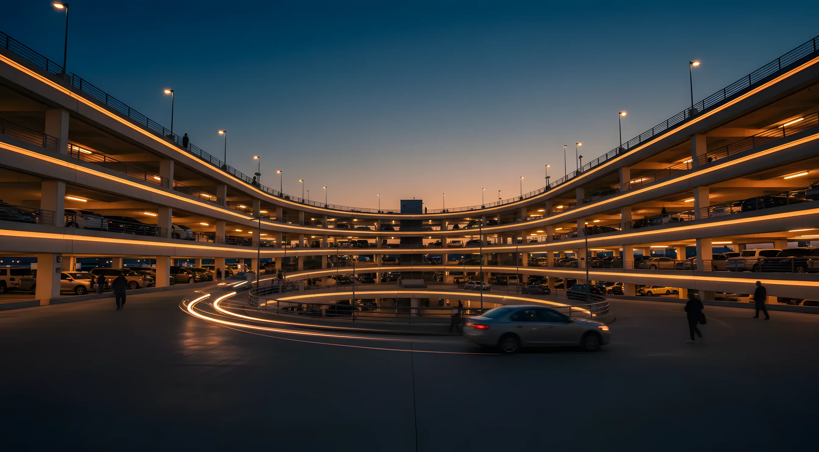 A modern multi-level airport parking garage illuminated with warm lights against a deep blue evening sky.