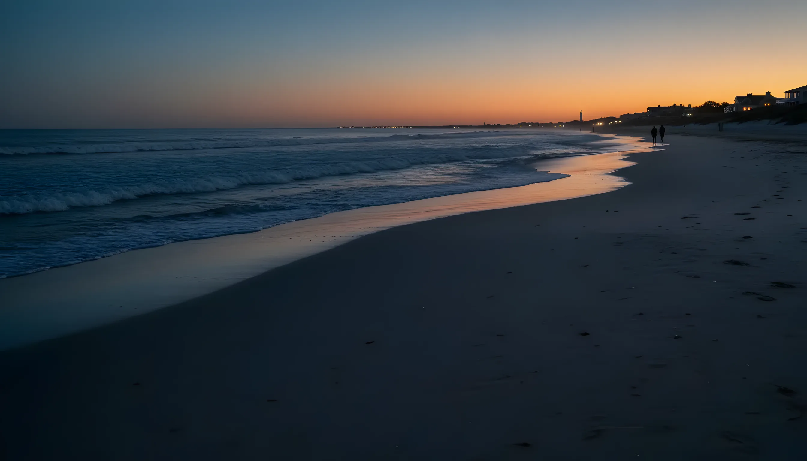 A calm, deserted Hamptons beach with white sand and blue-green water on a sunny day.