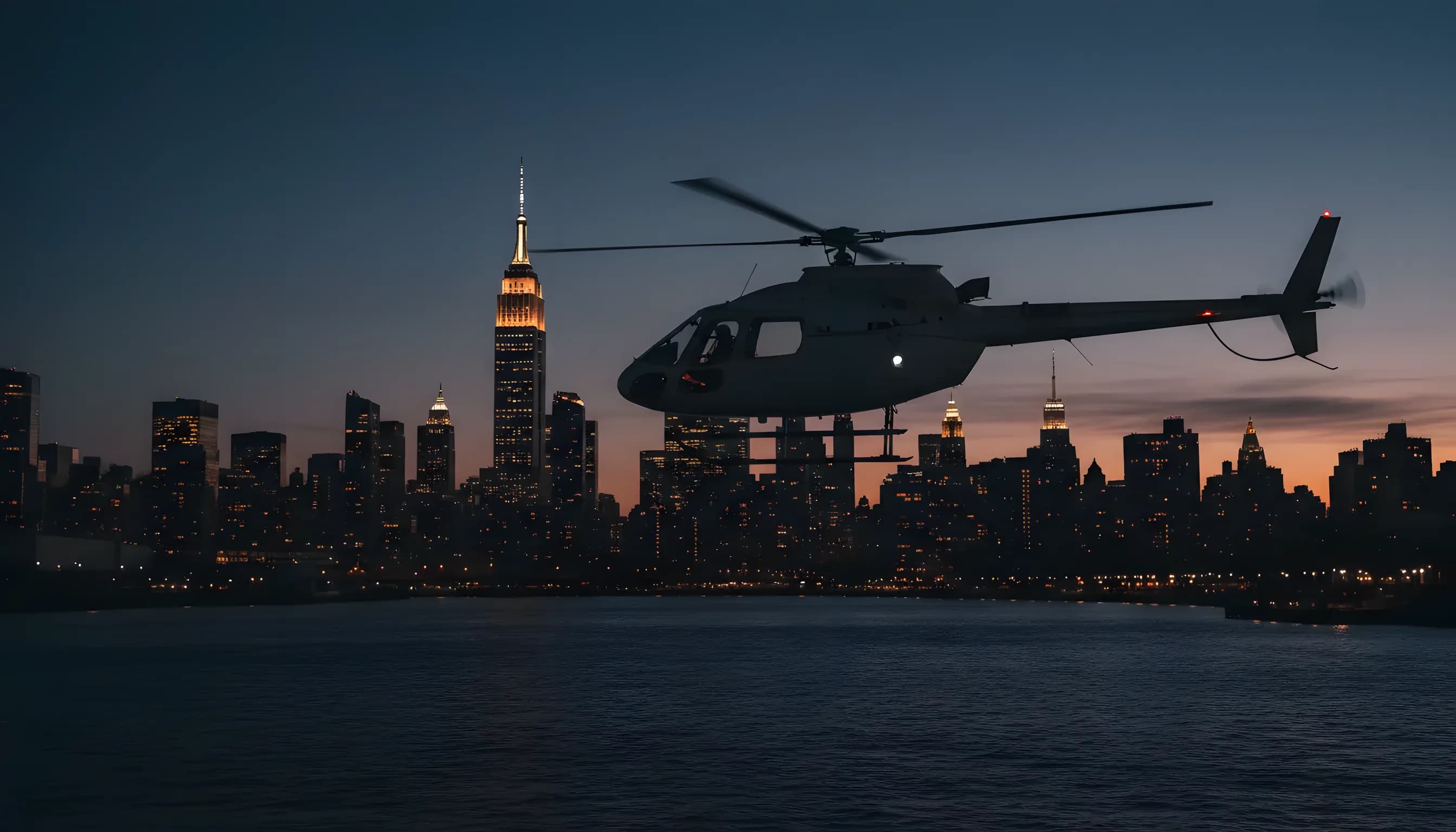 A helicopter flying over the East River at blue hour with the Midtown Manhattan skyline behind it.
