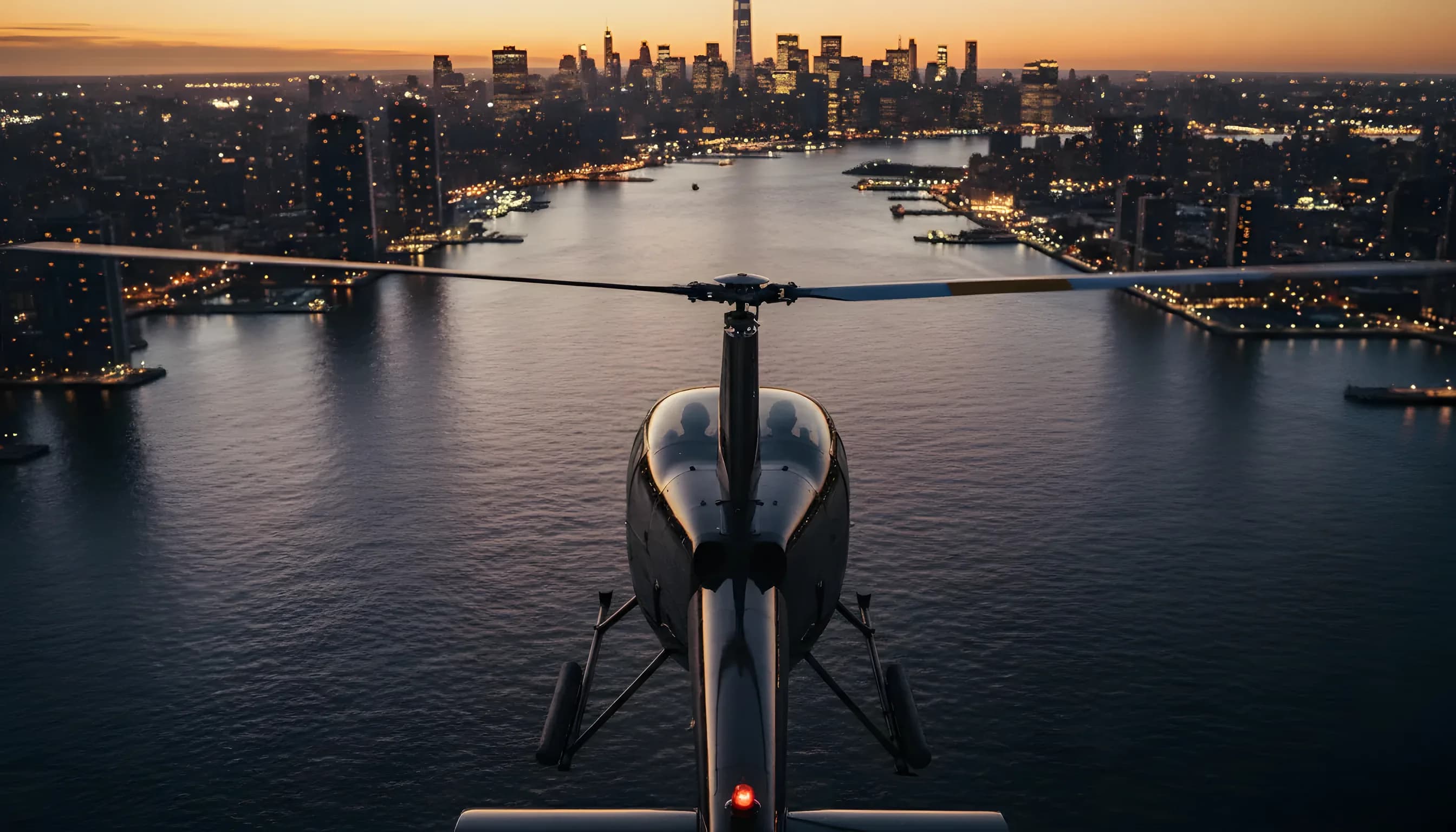 A helicopter flies towards the Manhattan skyline at dusk, with city lights beginning to glow.