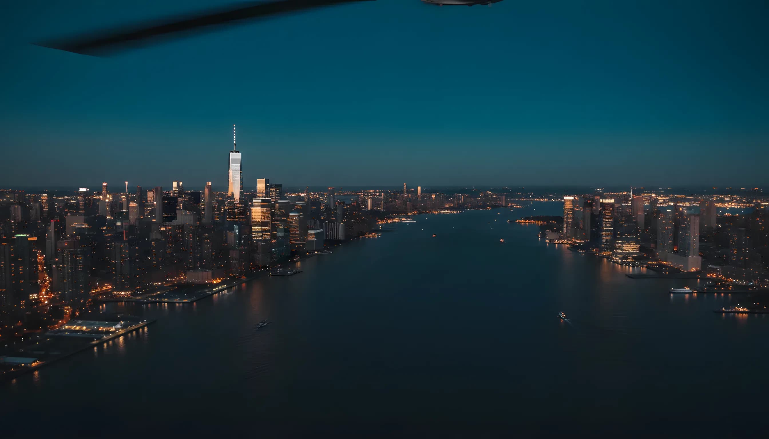 Aerial view of the Lower Manhattan skyline and Jersey City at dusk from over the Hudson River.