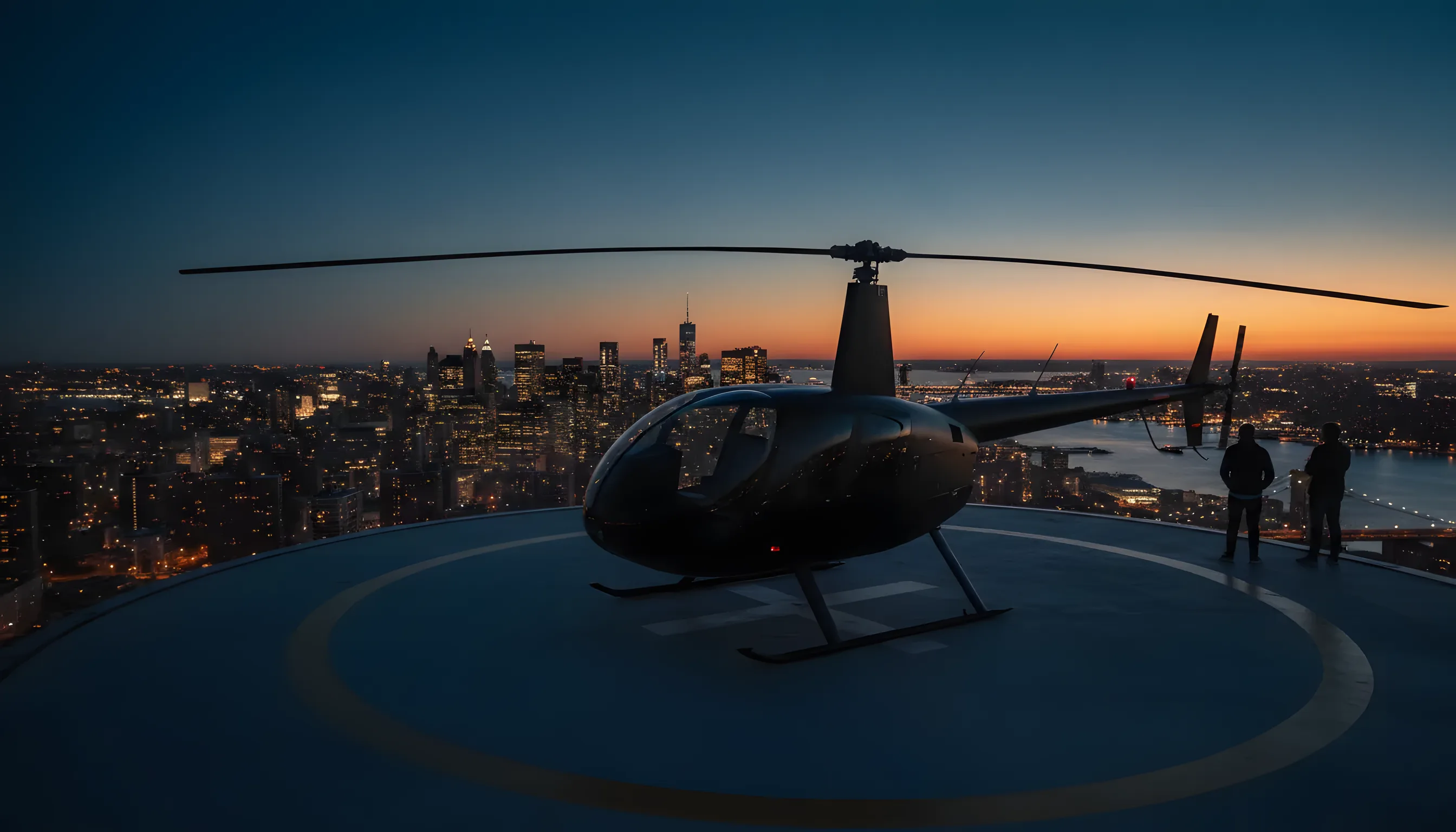 A helicopter on a rooftop helipad at dusk, with the lights of the Manhattan skyline in the background.