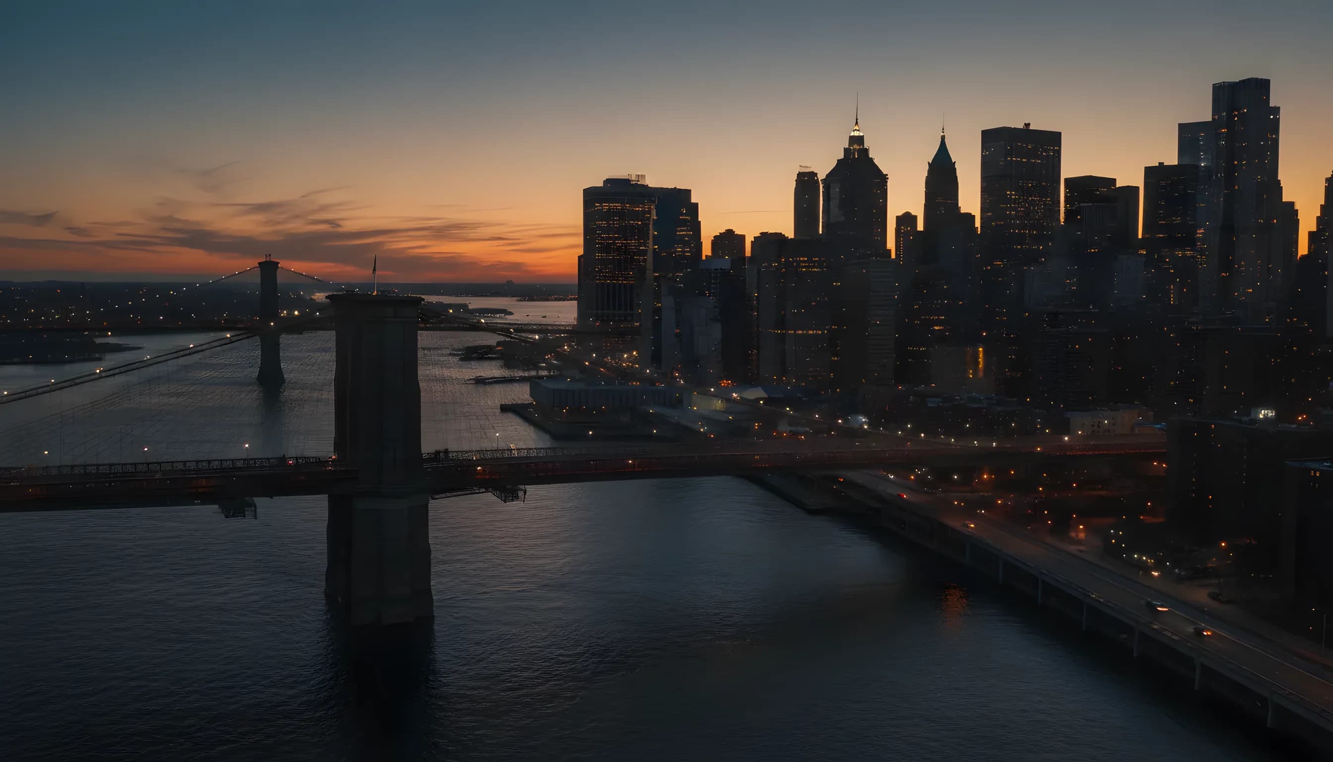 Aerial view of New York City bridges and the Brooklyn skyline at twilight.