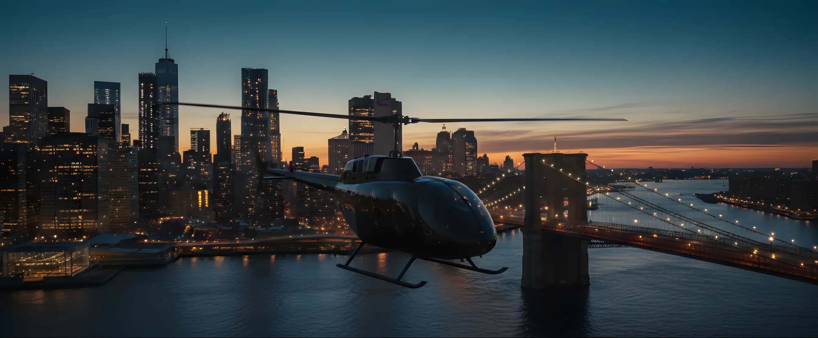 A helicopter flies over a river at dusk with the illuminated New York City skyline in the background.