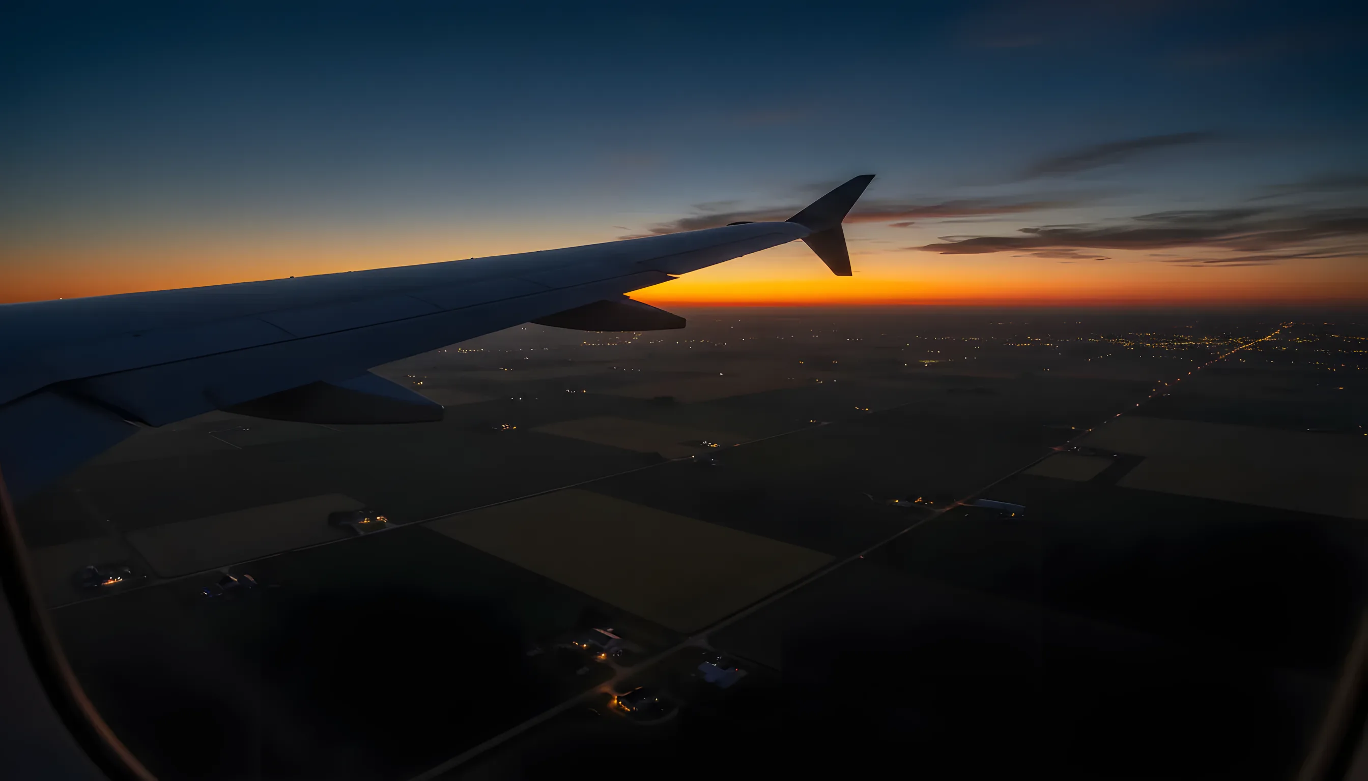 Aerial view from a private jet showing the wingtip over Iowa's patchwork farmland.