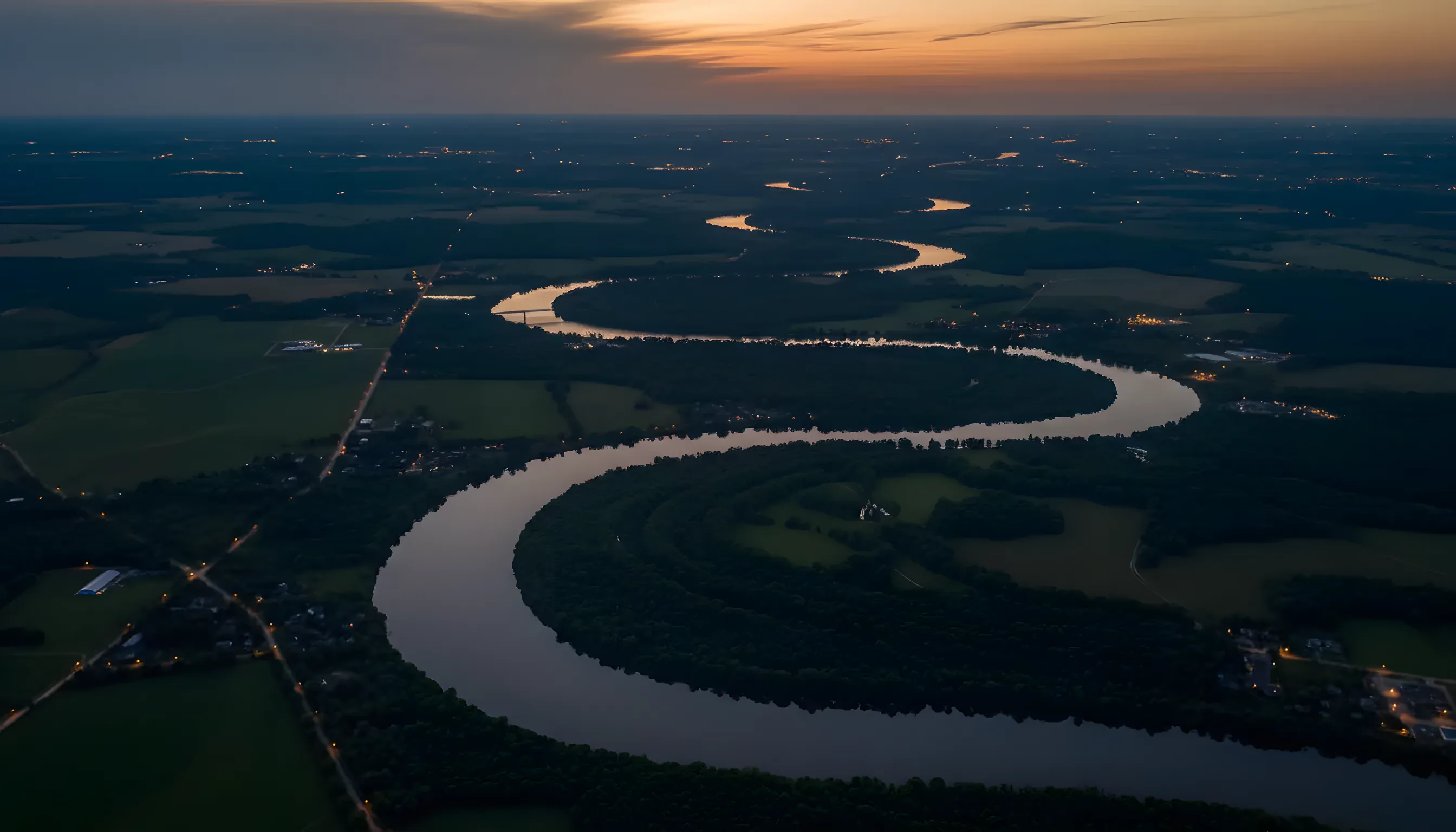 Aerial view of the sun glinting off the Mississippi River as it winds through farmland.