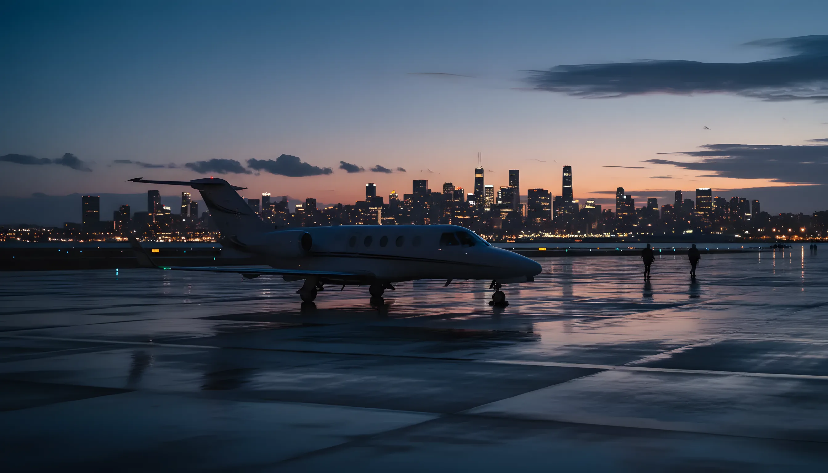A private jet on an airport tarmac at dusk, with a glowing city skyline in the distance.