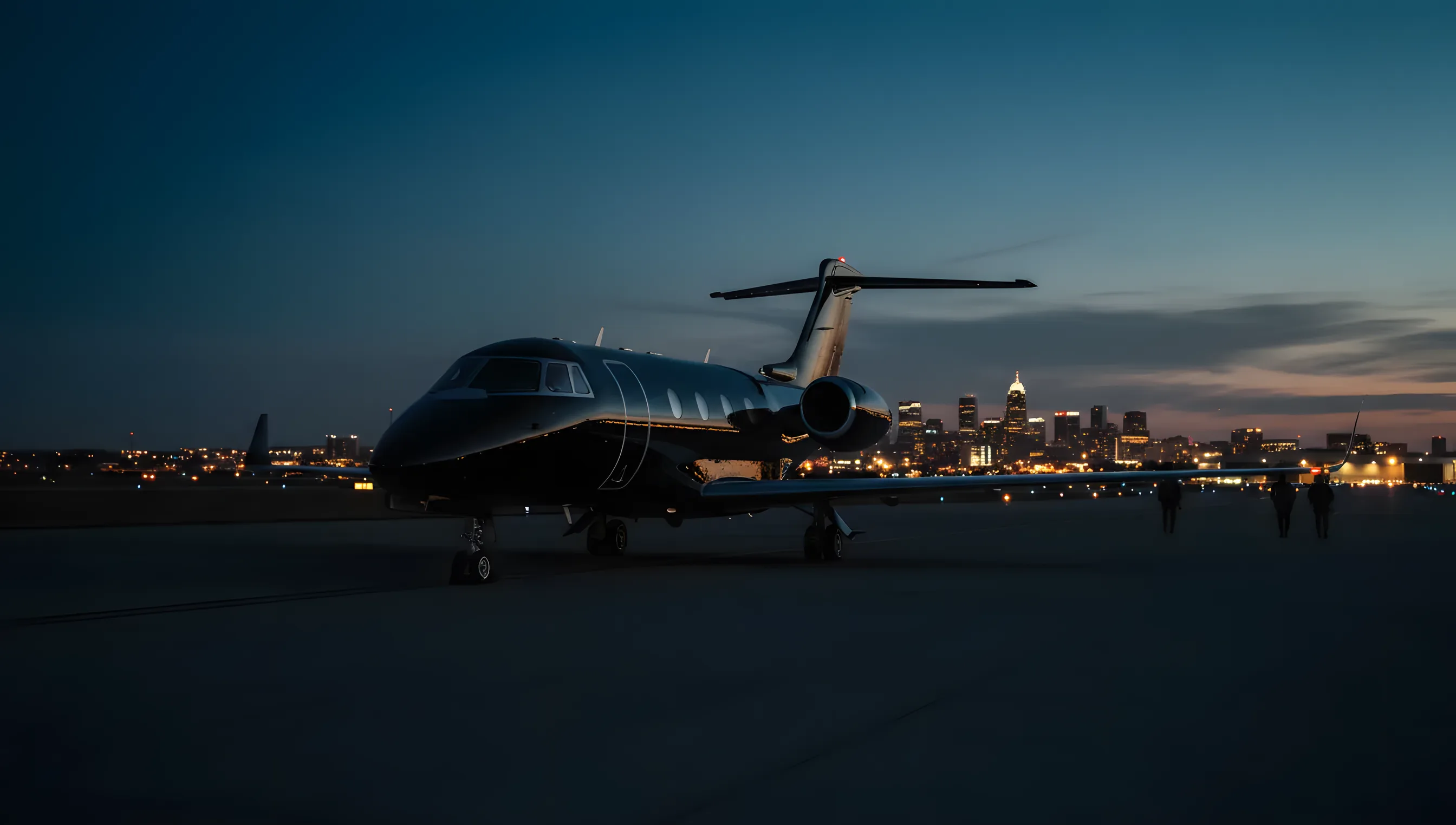 A private jet on an airport tarmac at dusk, with the lights of a city skyline in the distance.