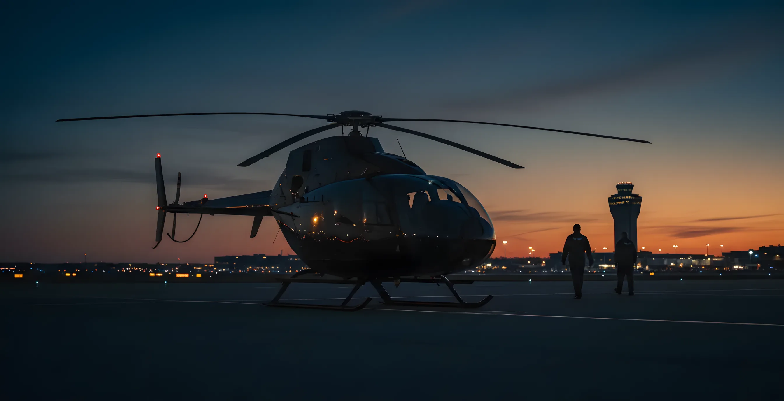 A helicopter parked on an airport tarmac at sunset, with a control tower in the background.