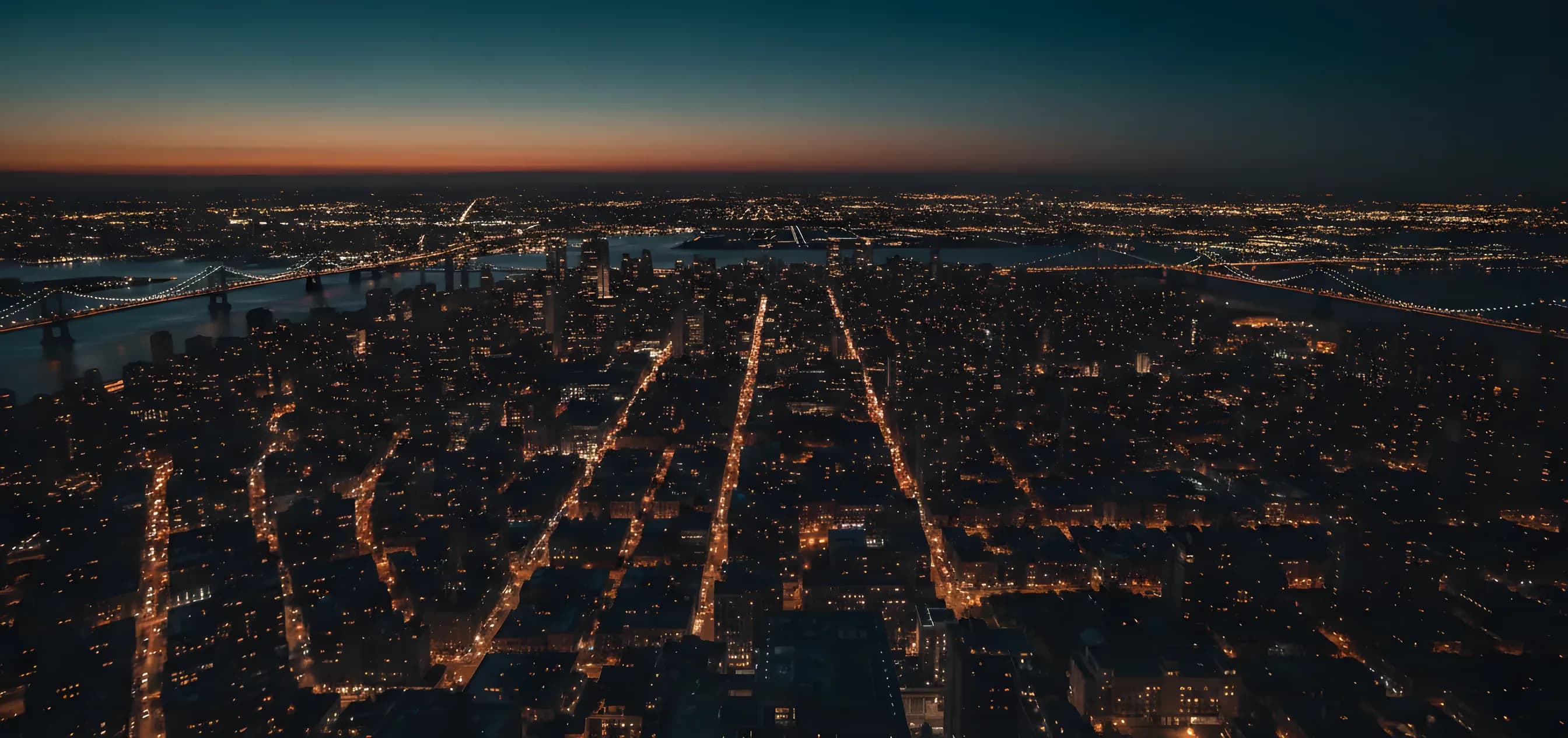 Aerial view of the Manhattan skyline at dusk, with city lights beginning to glow.