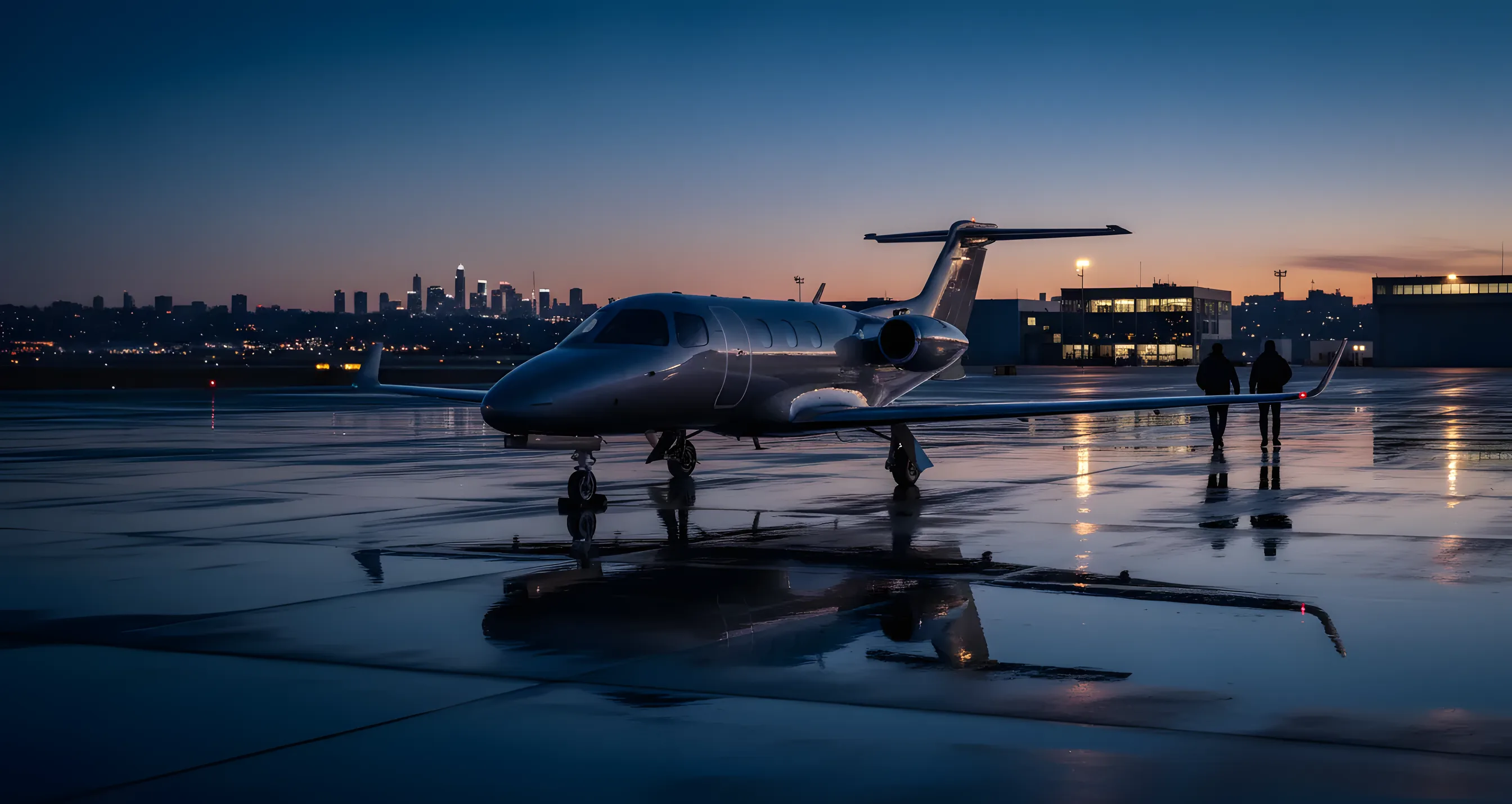 A private jet on an airport tarmac at dusk, with city lights in the distance.