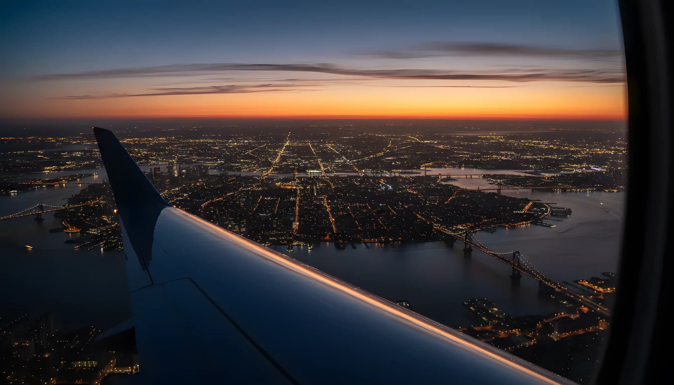 Aerial view of the Manhattan skyline at dusk from a private jet window.
