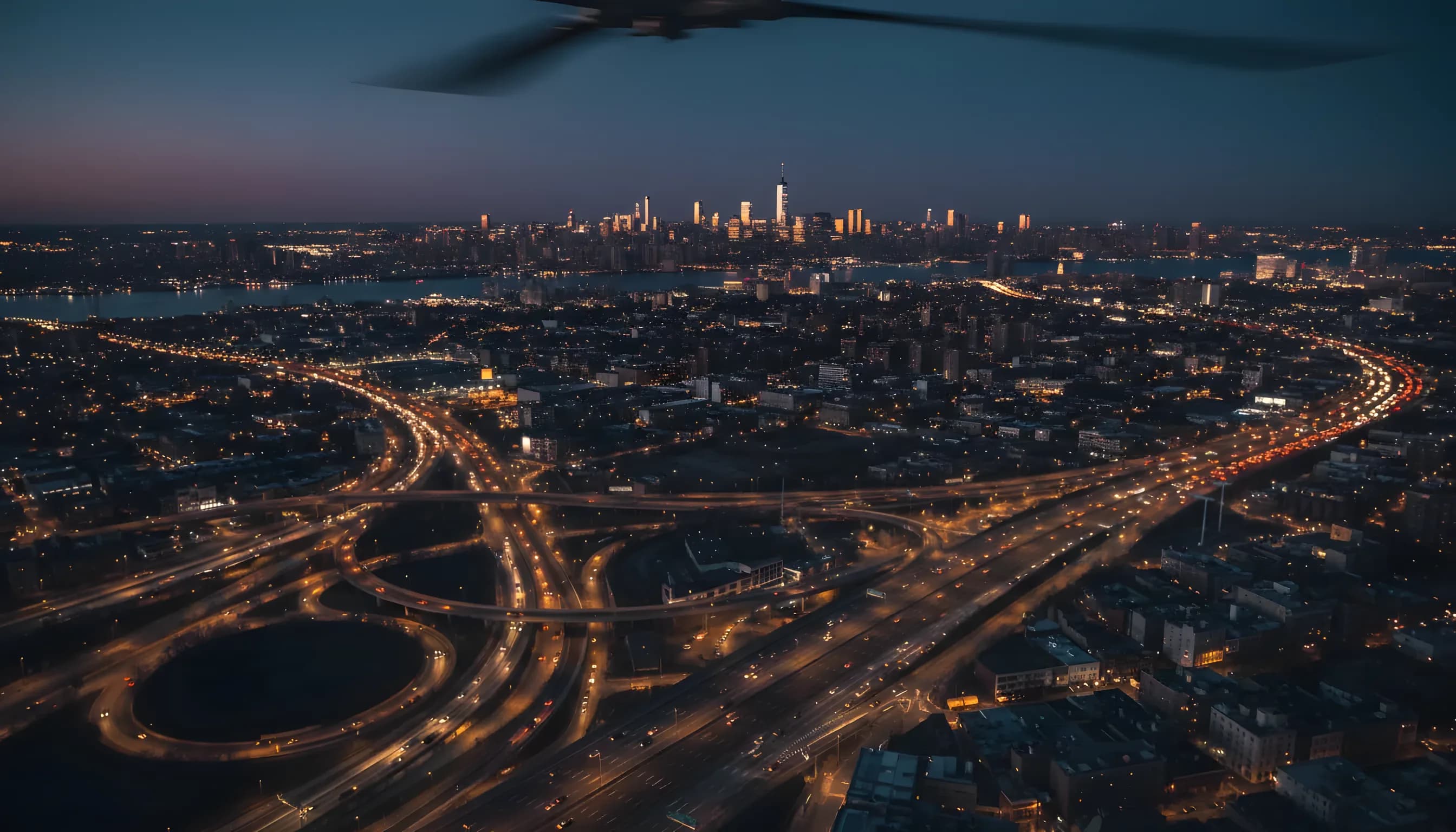 Aerial view of the Manhattan skyline at dusk, seen from above Queens with city lights below.