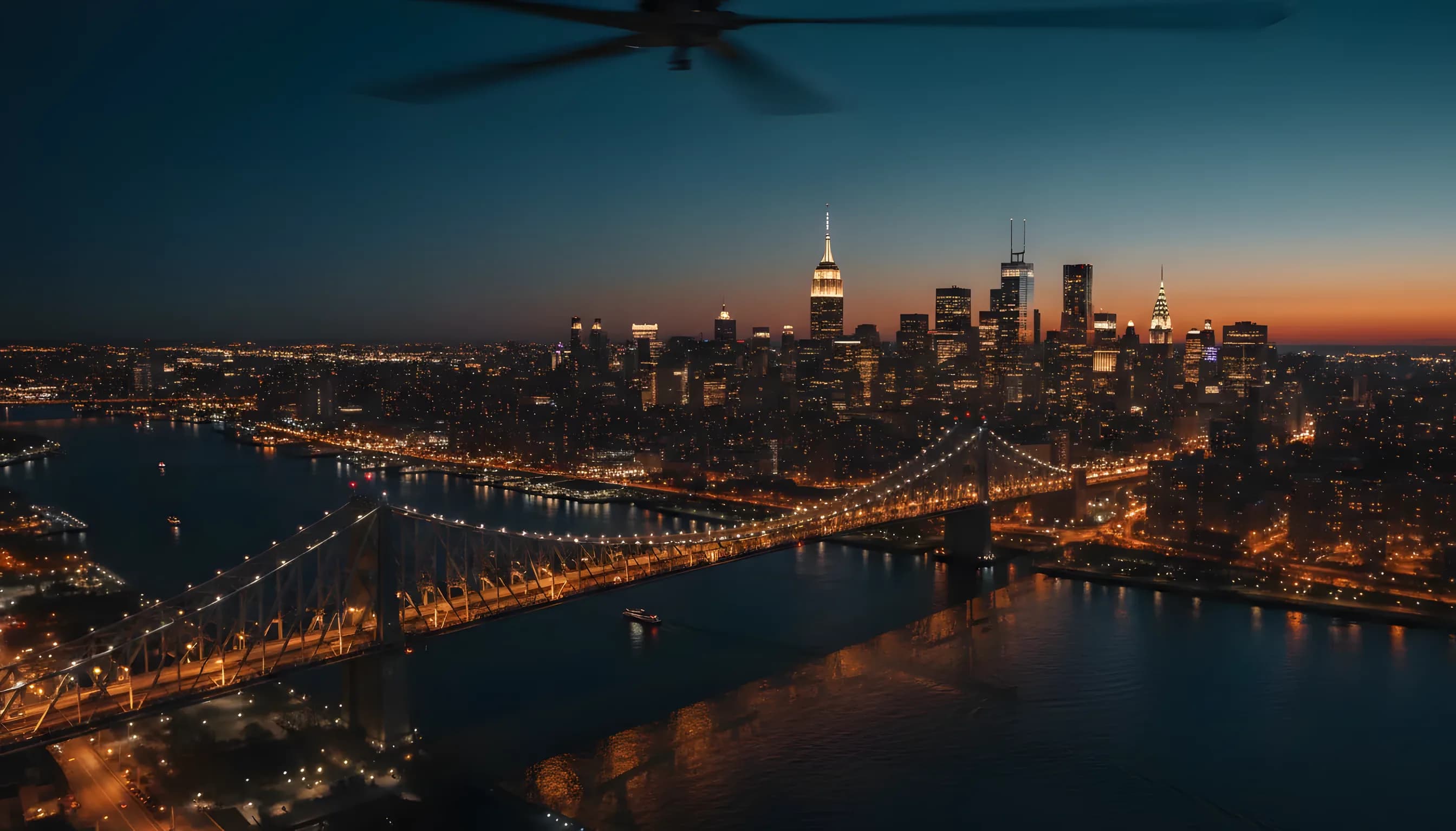 Aerial view of the Manhattan skyline and a bridge at dusk, with city lights glowing against the dark sky.