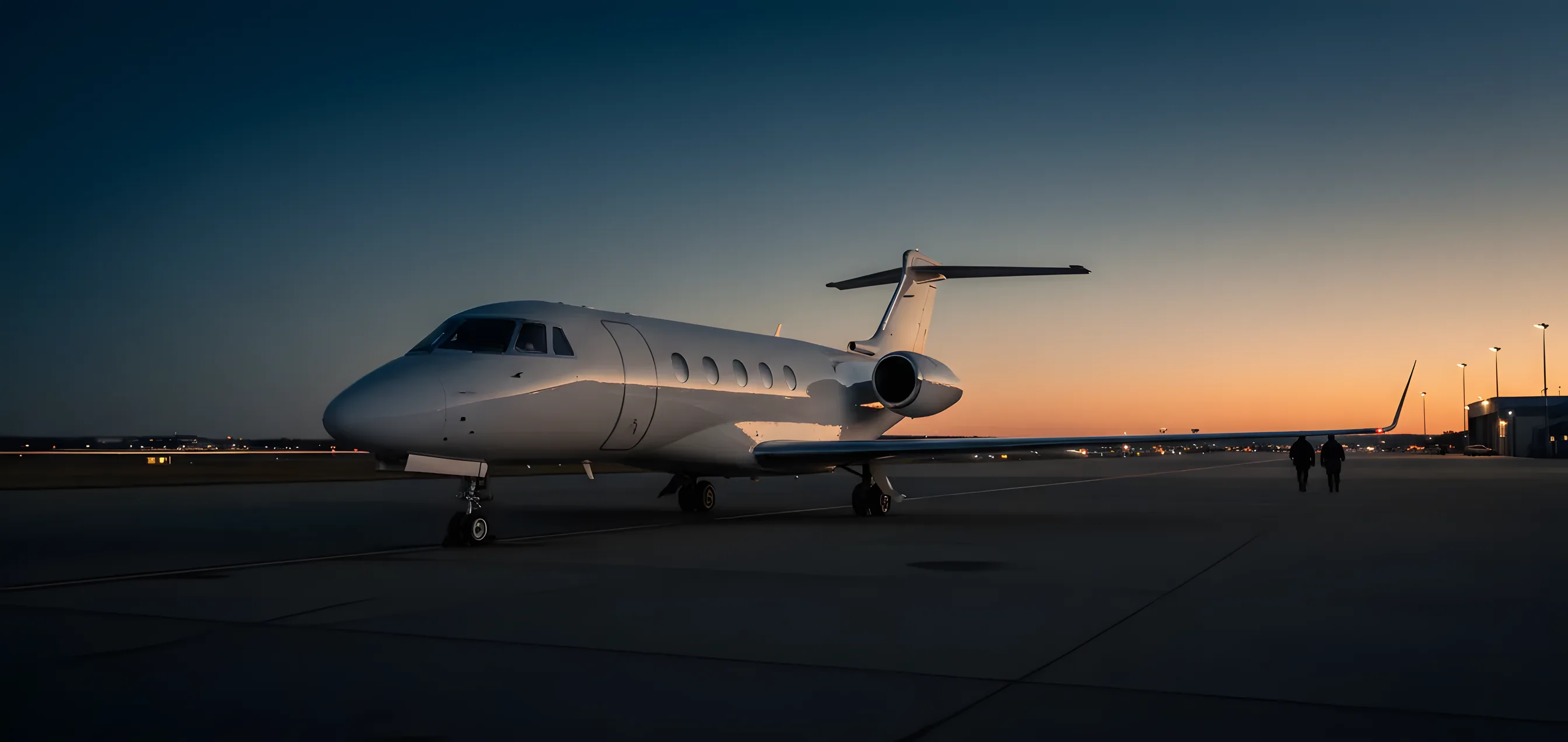 A sleek private jet parked on an airport tarmac at sunrise.