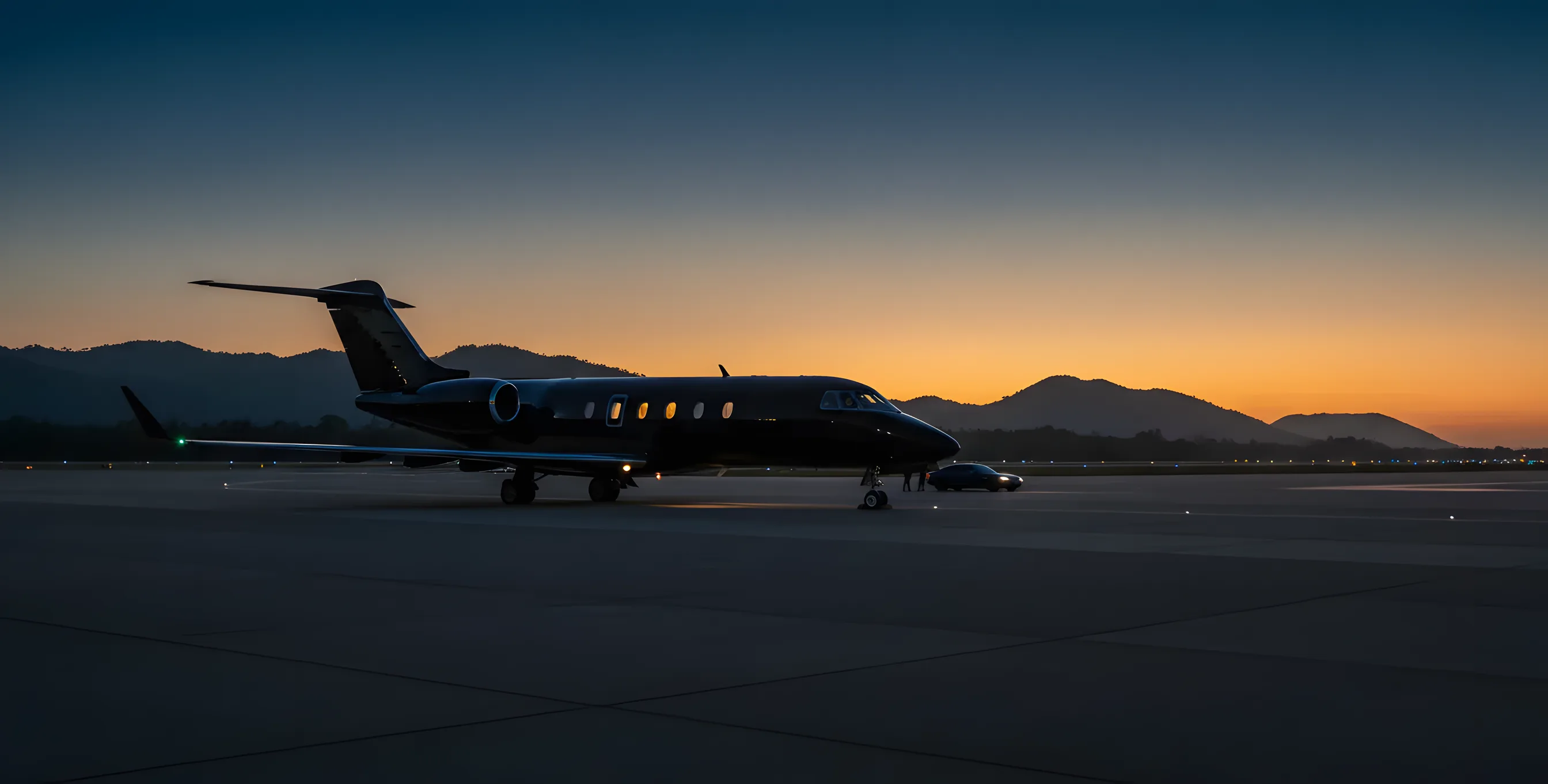 A private jet on a tarmac at dusk with tropical hills in the background.