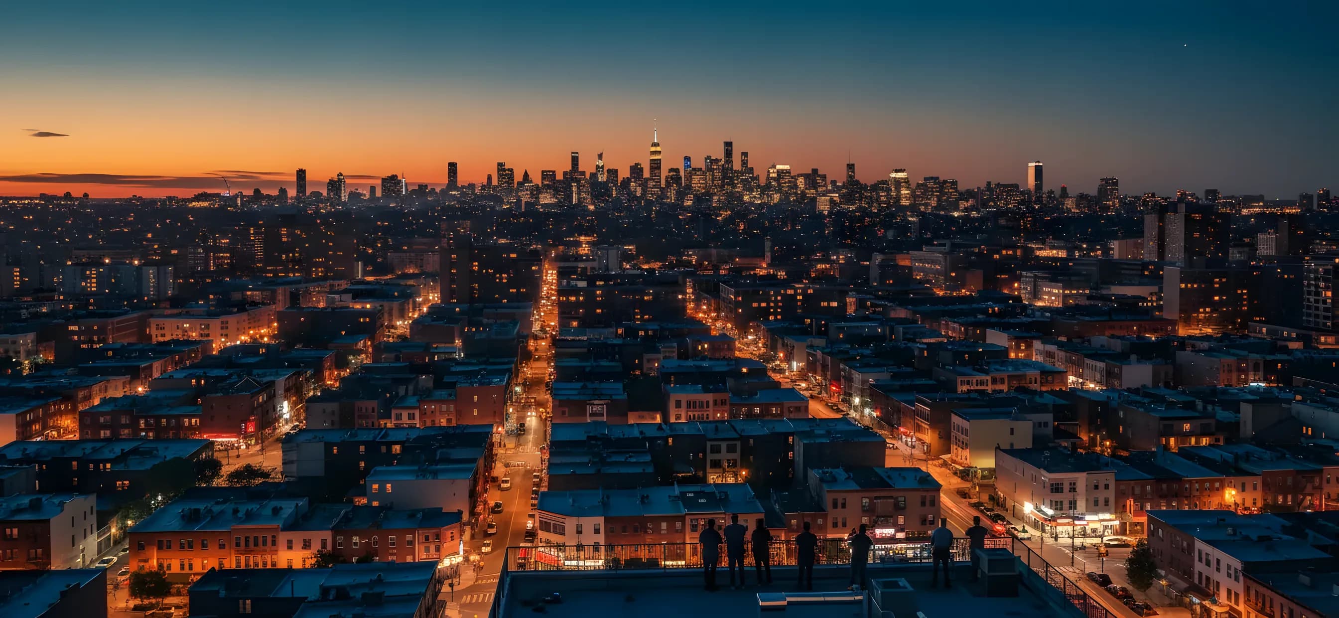 A rooftop view from Bushwick at dusk, with the glowing Manhattan skyline visible in the distance.