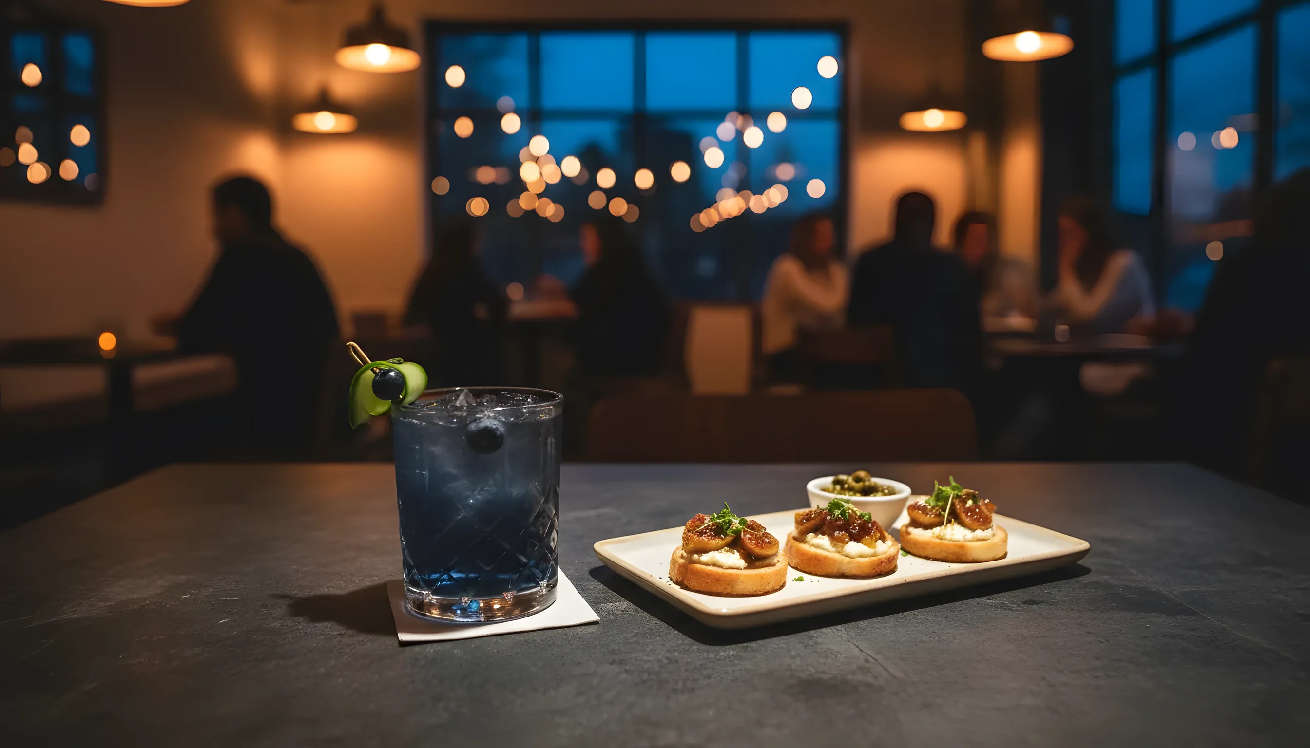 A craft cocktail and appetizers on a slate table at a chic Williamsburg cafe.