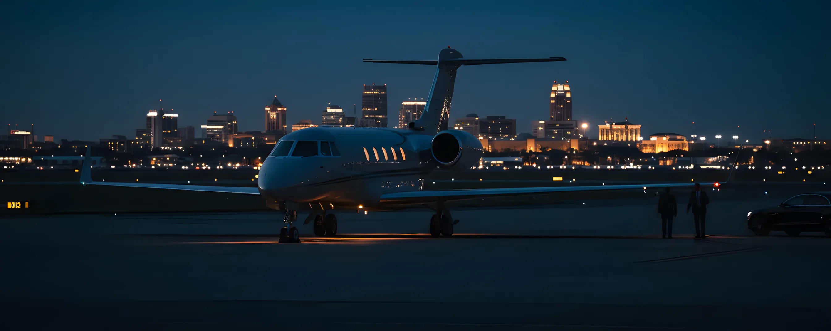 A private jet on an airport tarmac at dusk, with the lights of Gainesville, Florida, in the distance.