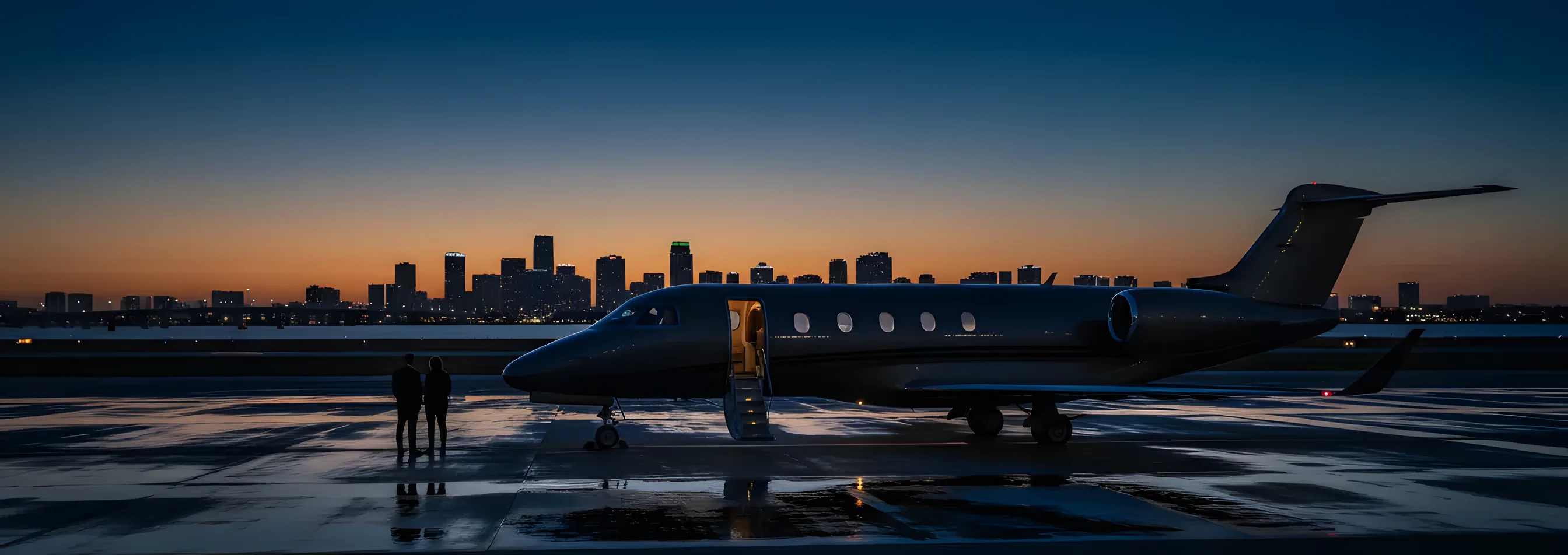 A private jet on an airport tarmac at dusk, with a city skyline in the background.