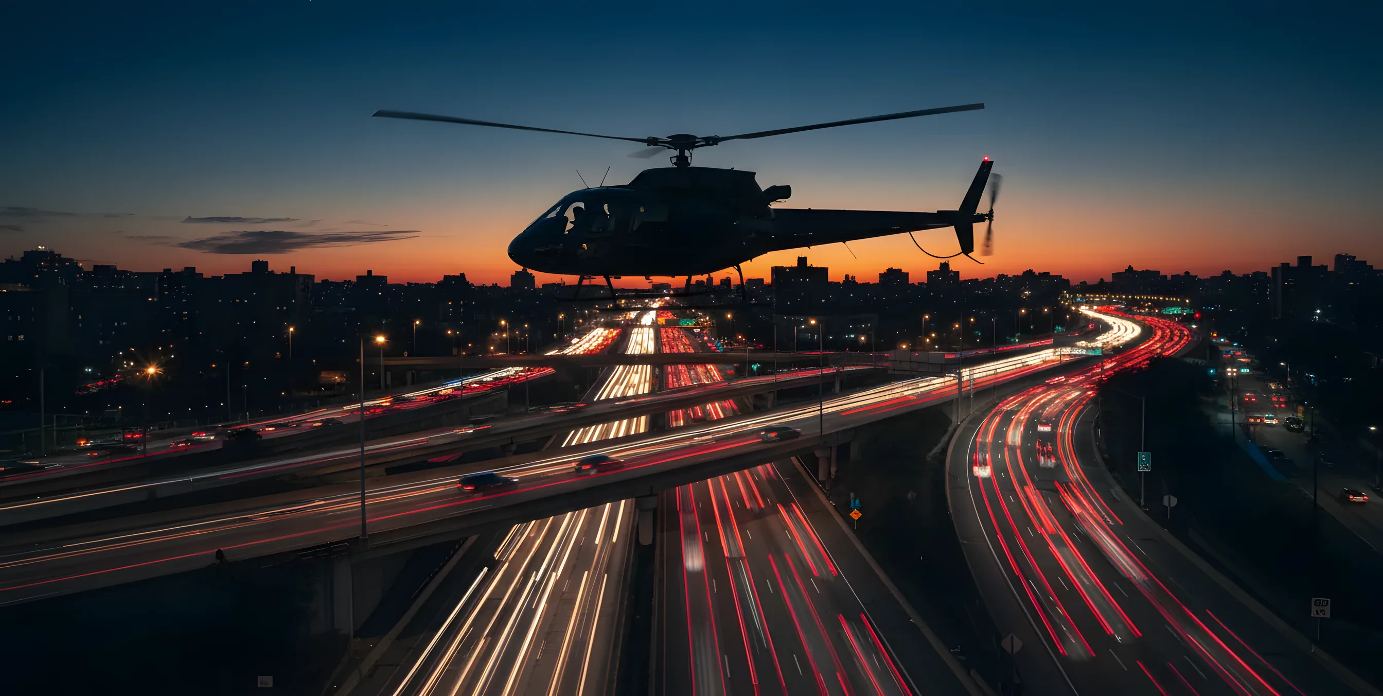 A helicopter flies over a New York City highway with heavy traffic at dusk.