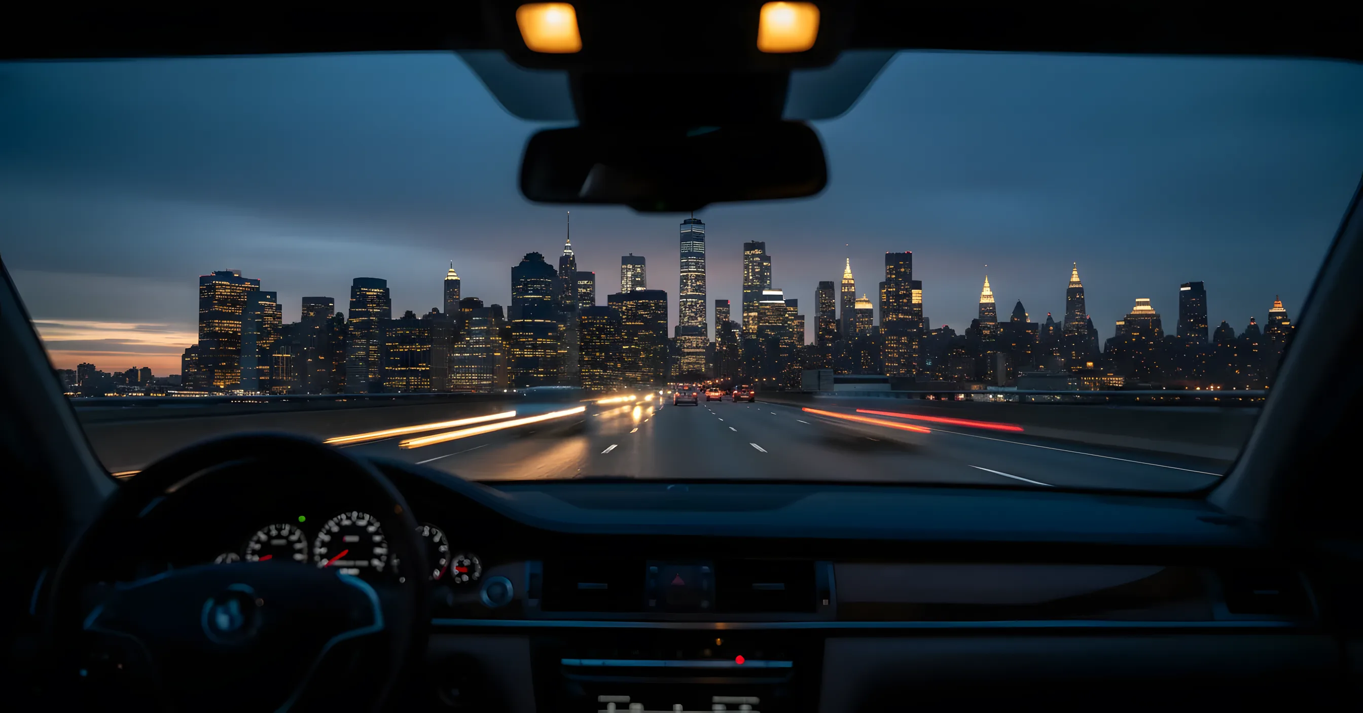 The Manhattan skyline seen from a car on a highway at dusk.