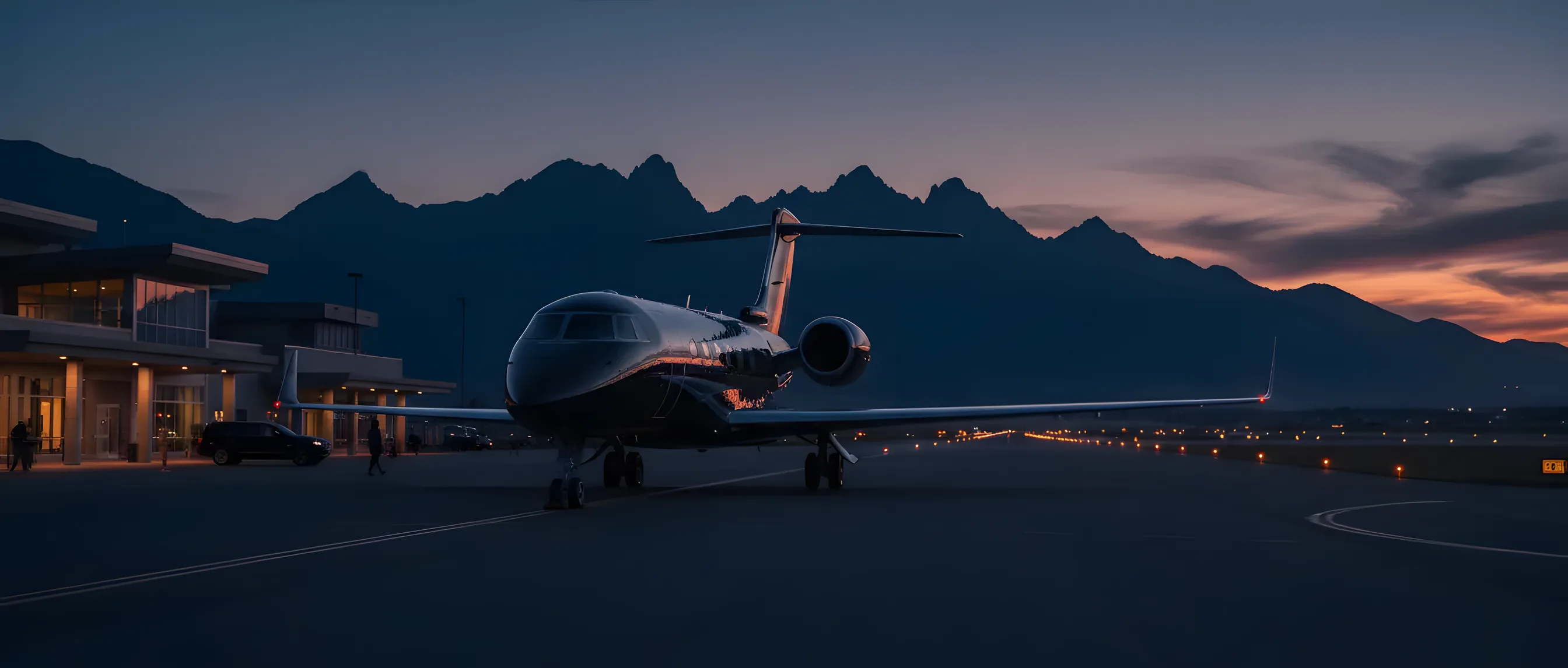 A private jet on an airport tarmac at dusk, with mountains in the background.