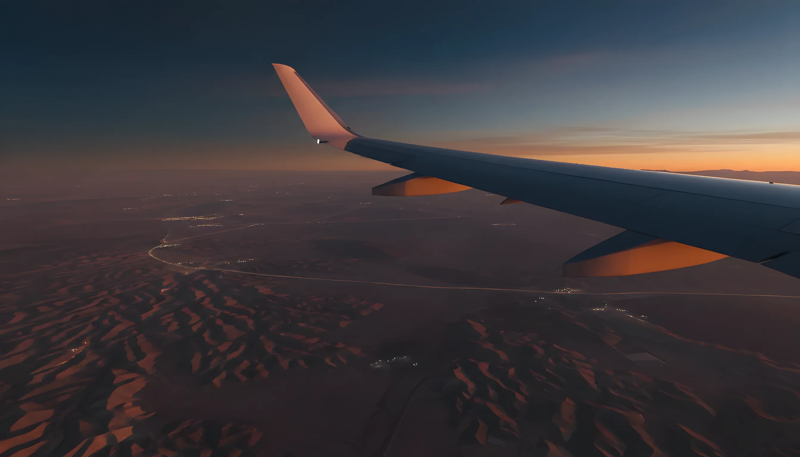 View of the Nevada desert landscape from a private jet window, with the aircraft's wing visible against the golden terrain.