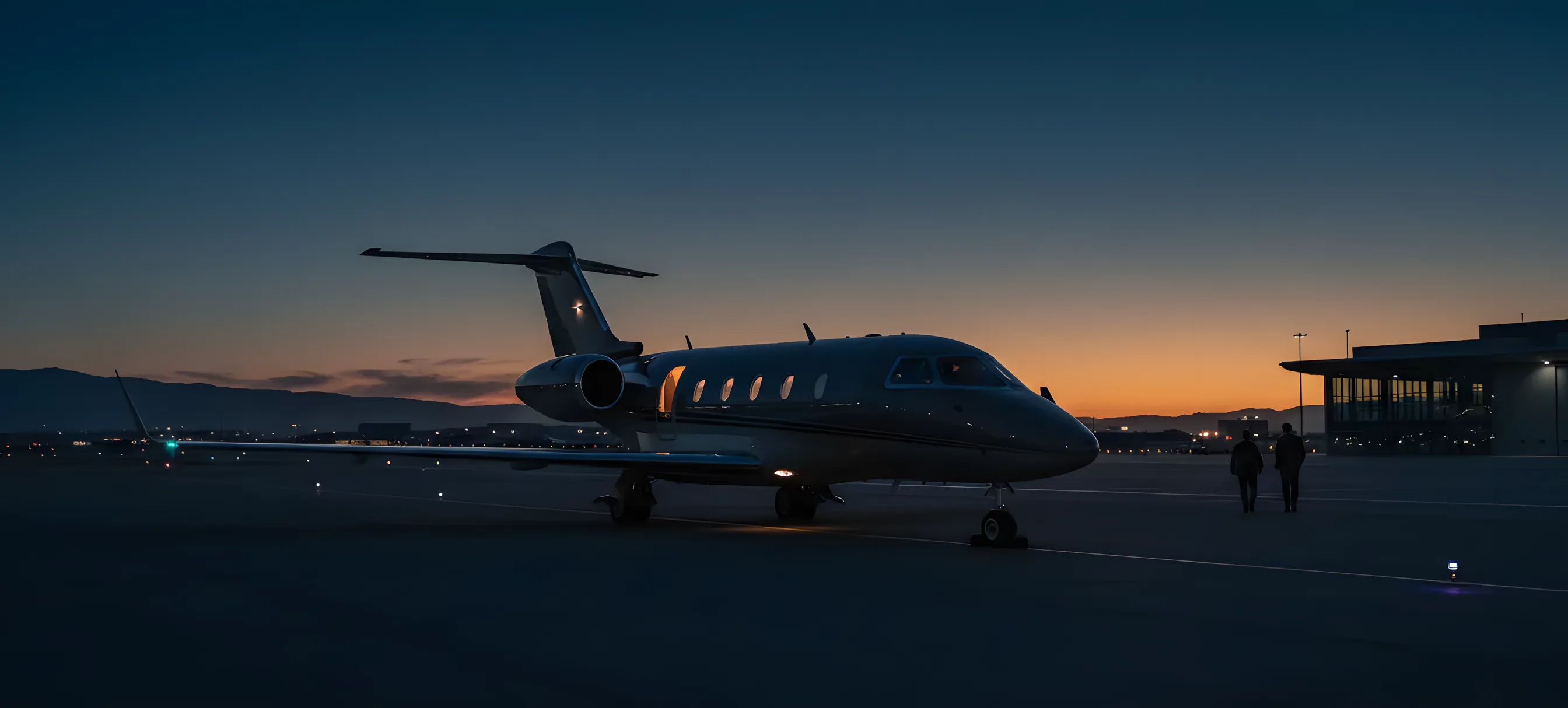 A private jet sits alone on an empty airport tarmac at sunrise.