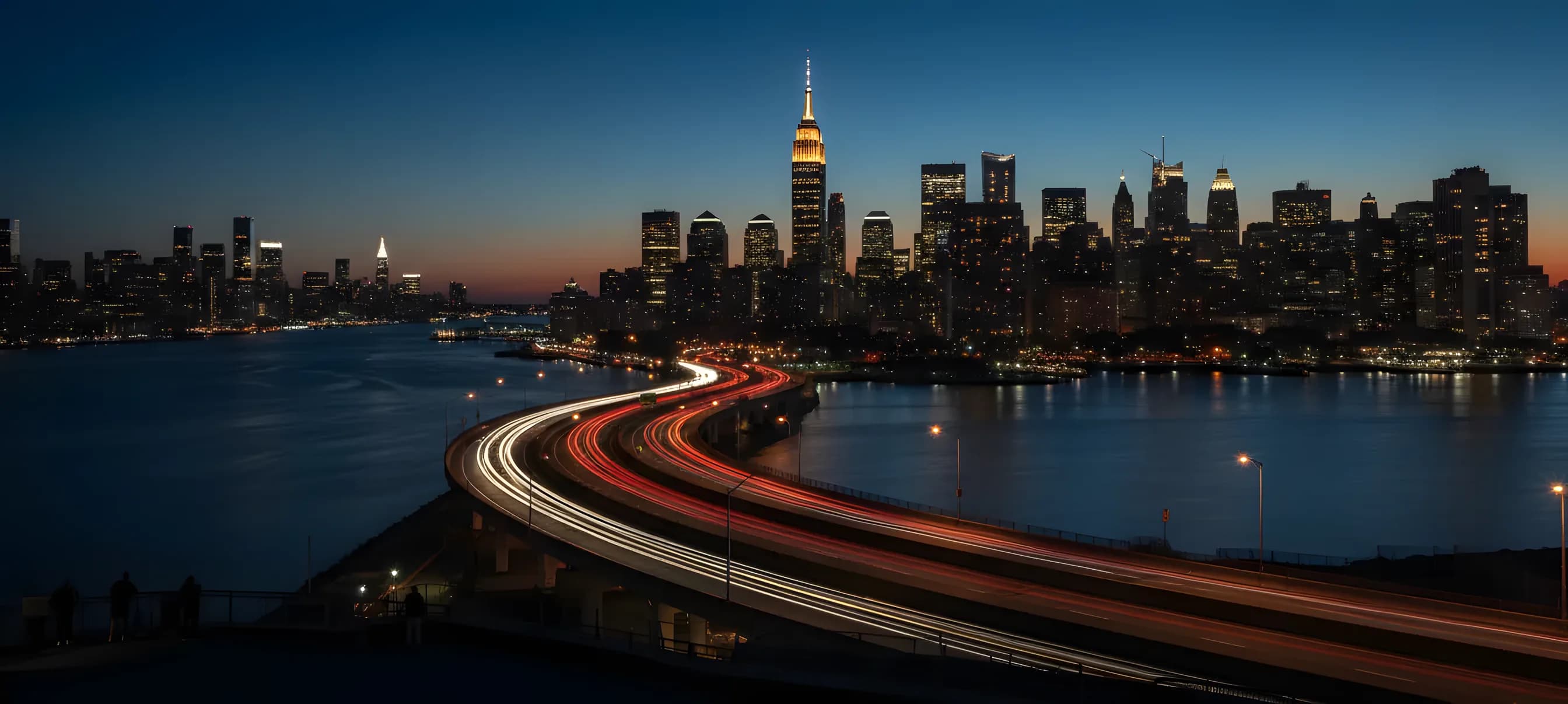 The Manhattan skyline at dusk, with the Empire State Building illuminated, as seen from across the river in New Jersey.