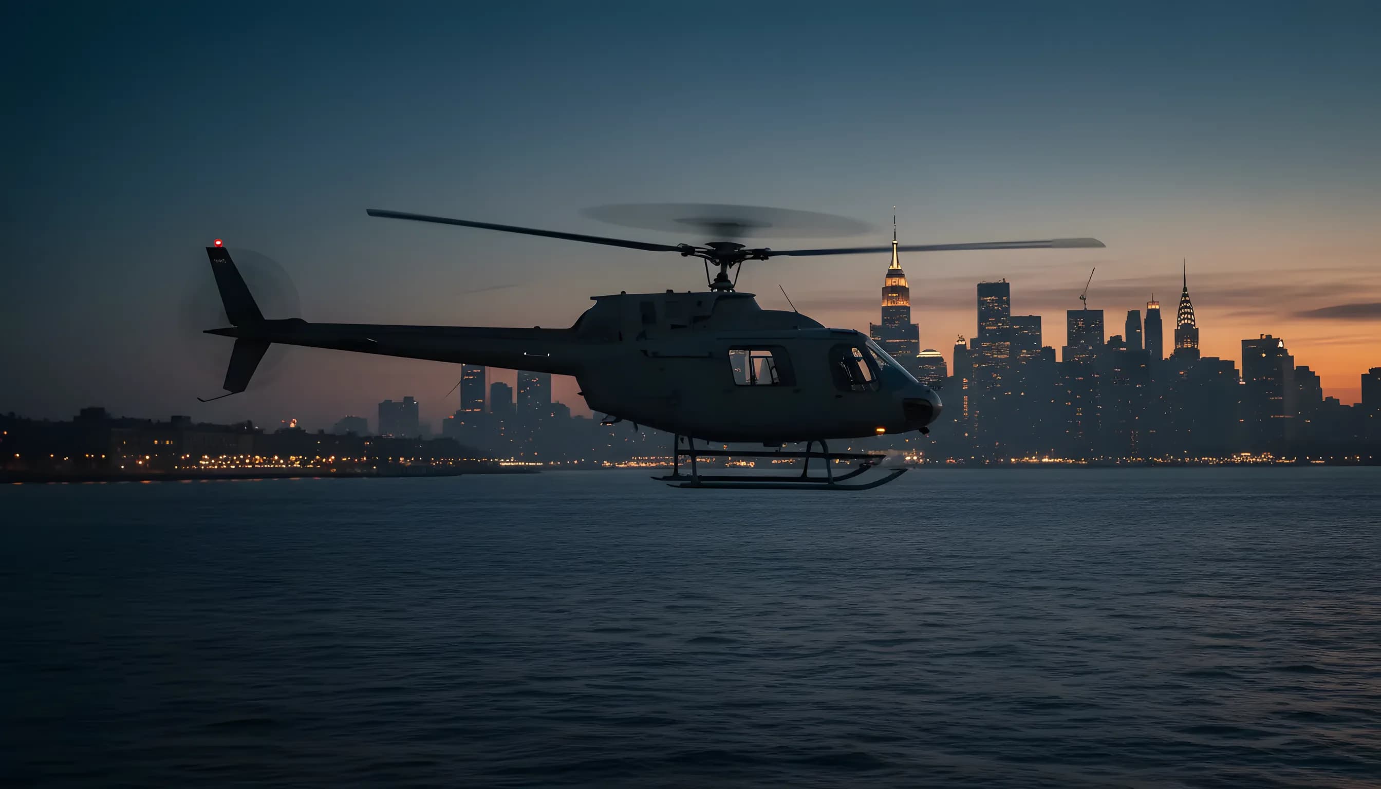 A helicopter flying over the Hudson River toward the Midtown Manhattan skyline at blue hour.