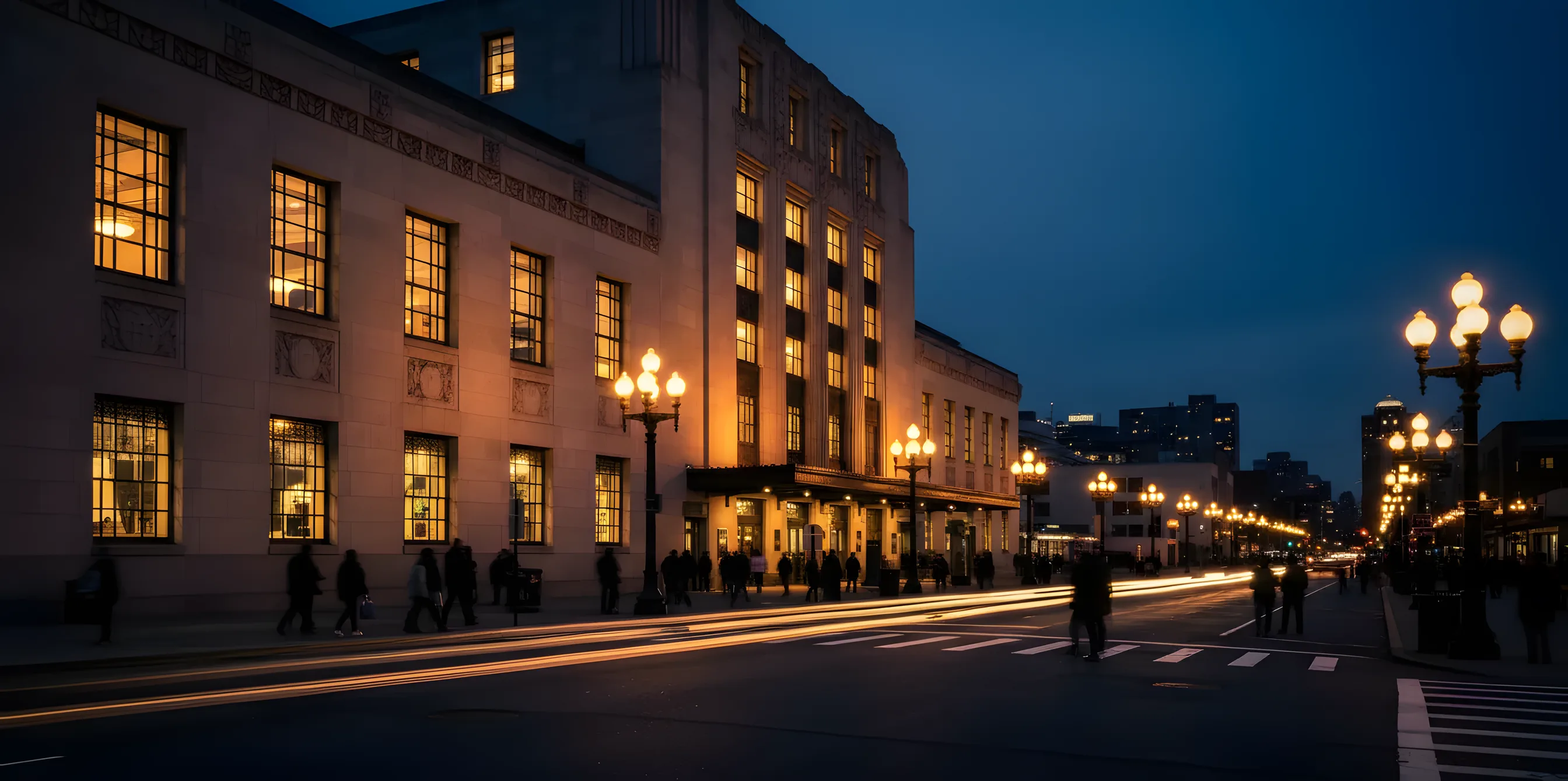 The historic Art Deco facade of Newark Penn Station illuminated at dusk against a deep blue sky.