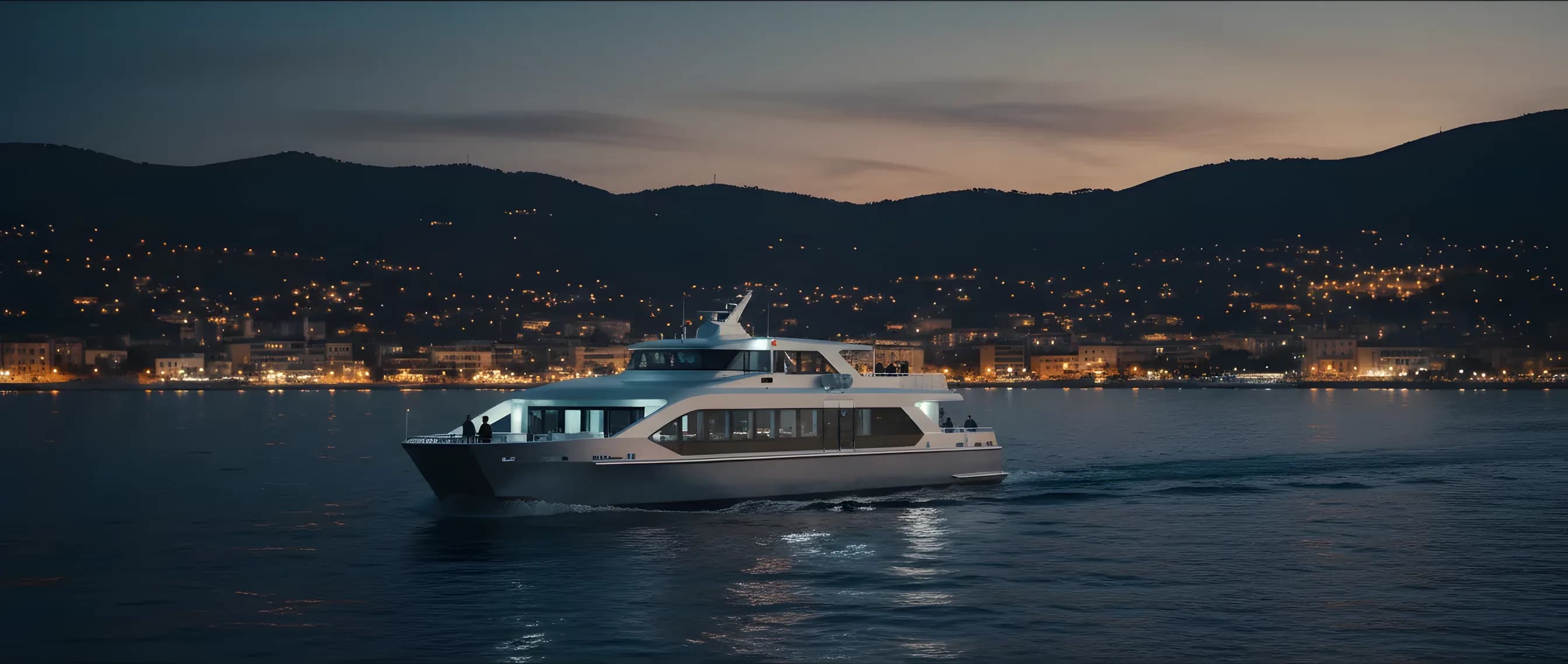 A modern ferry sails along the French Riviera coast at dusk as city lights begin to glow.