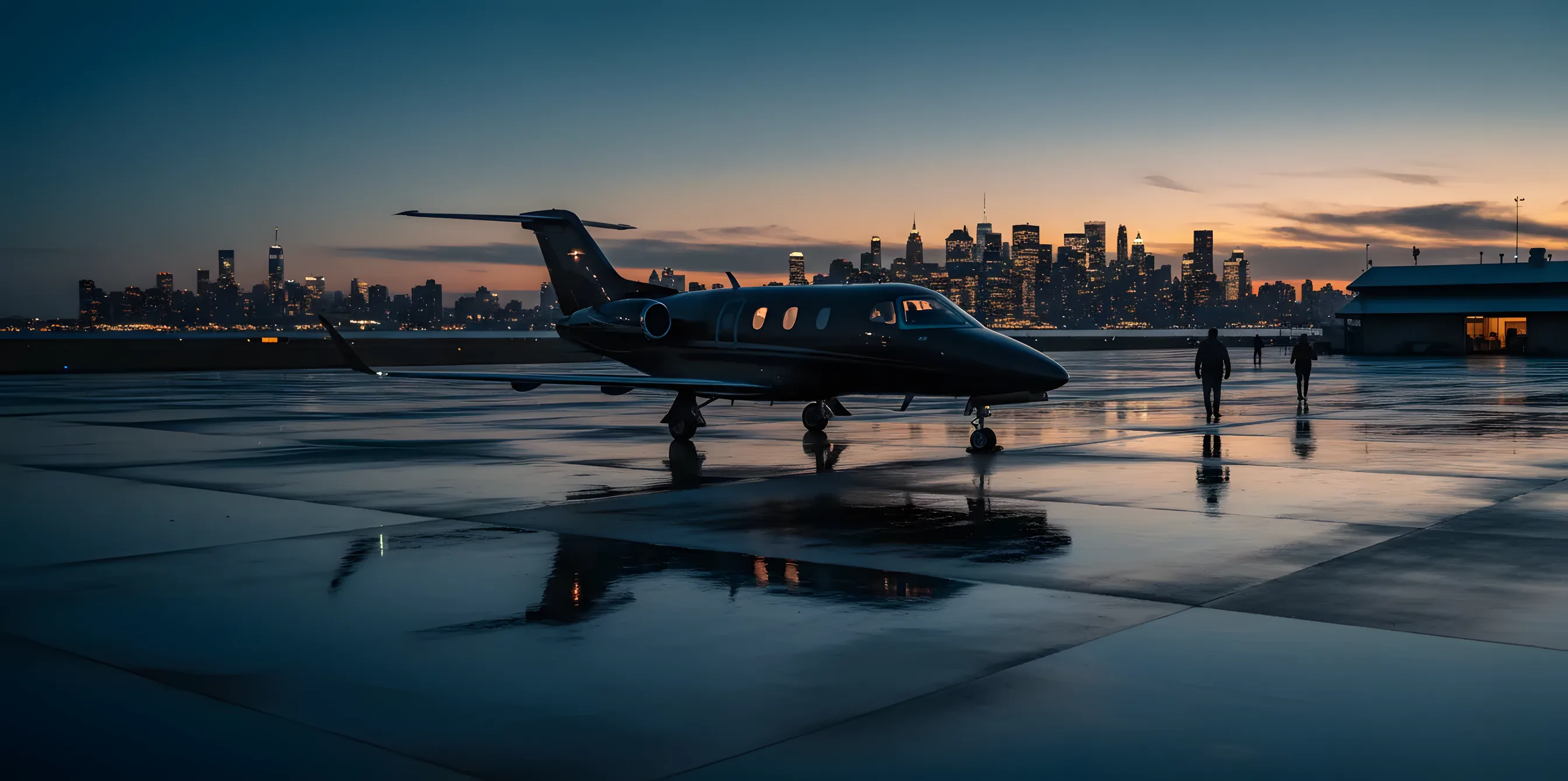 A private jet on an airfield at dusk, with a city skyline in the background.