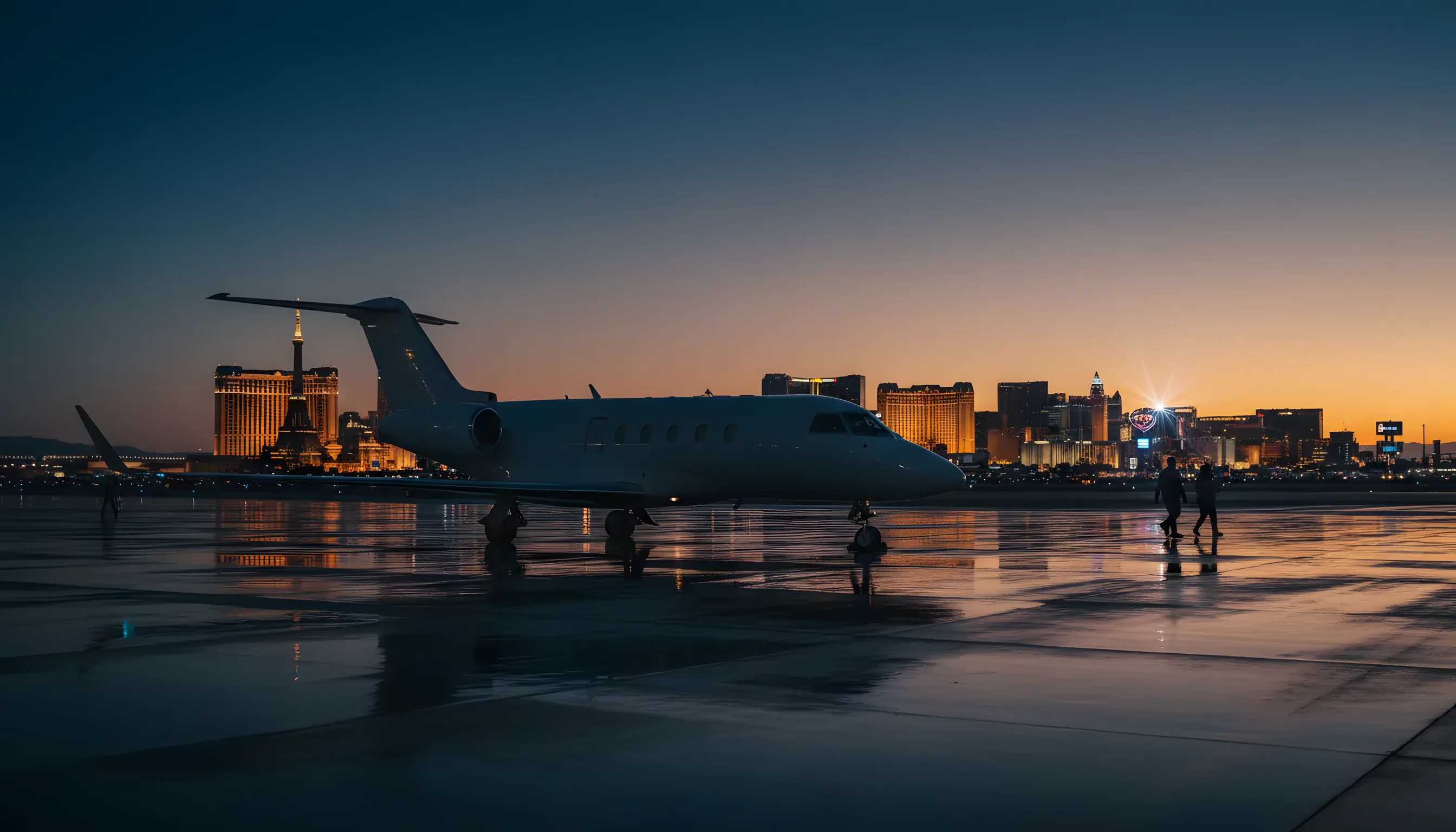 A private jet on an airport tarmac at dusk, with the glowing Las Vegas skyline in the distance.