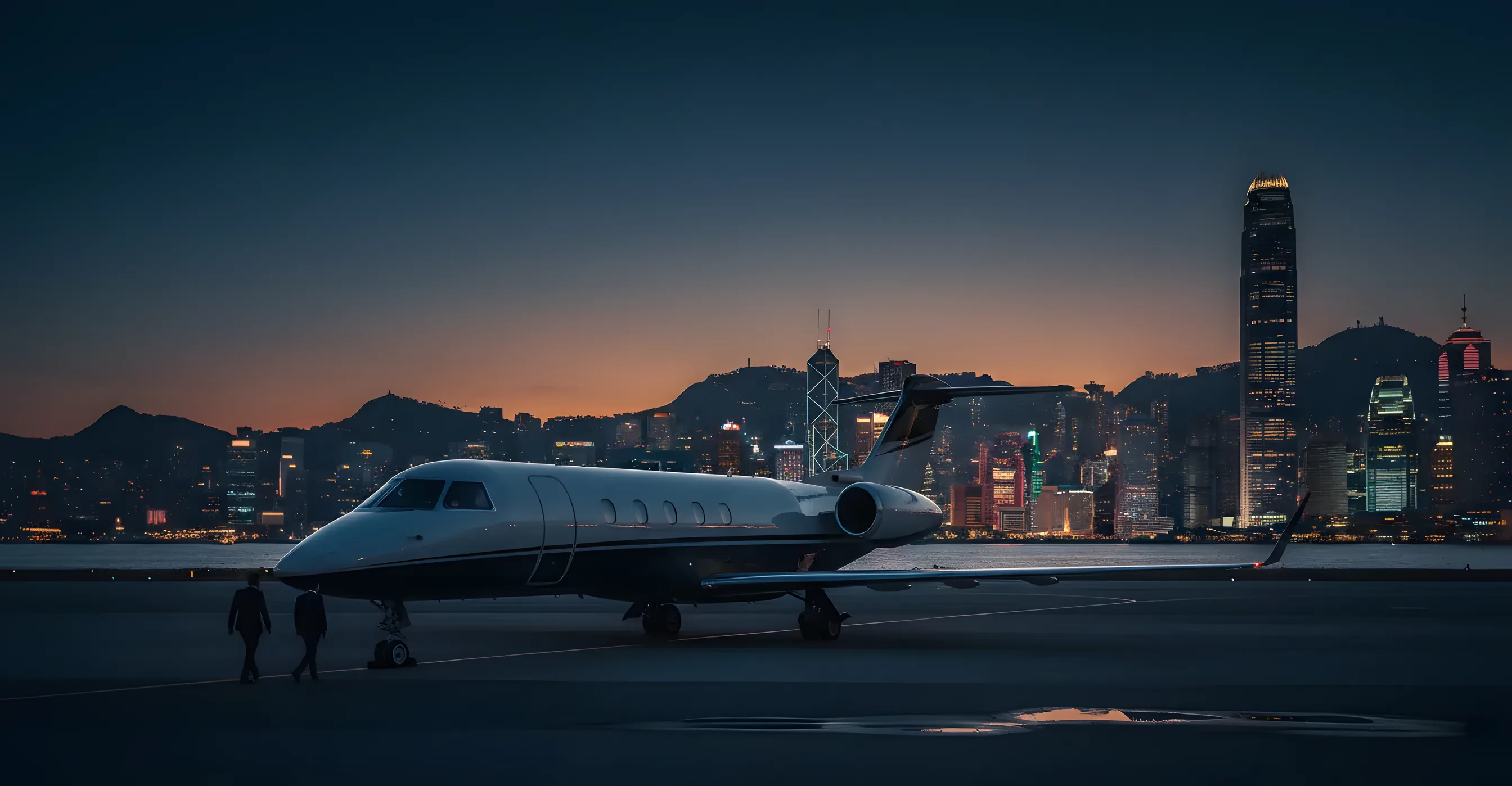 A private jet on an airport tarmac at dusk with the glowing Hong Kong skyline in the background.