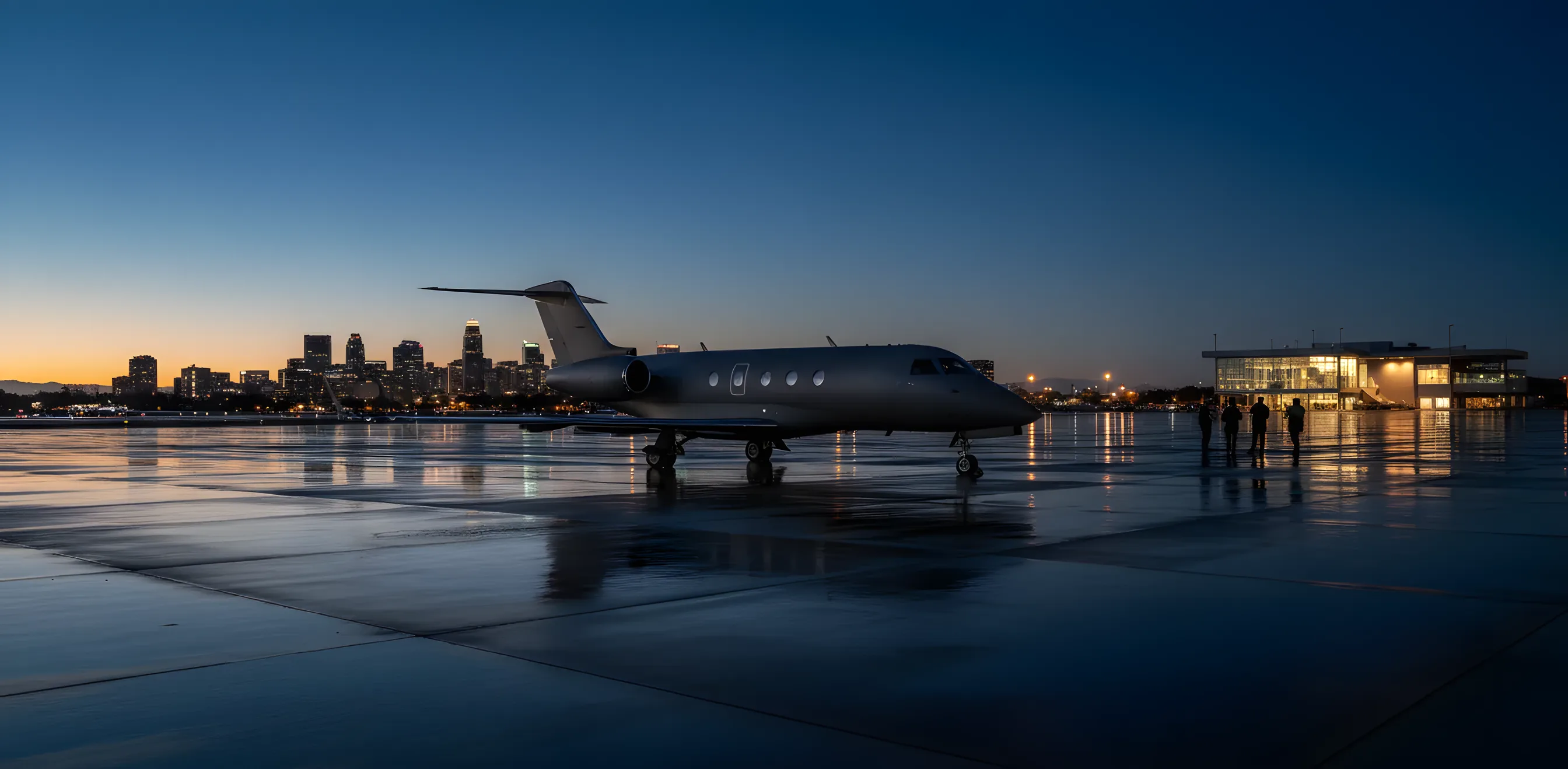 A private jet on an airport tarmac at dusk with a city skyline in the background.
