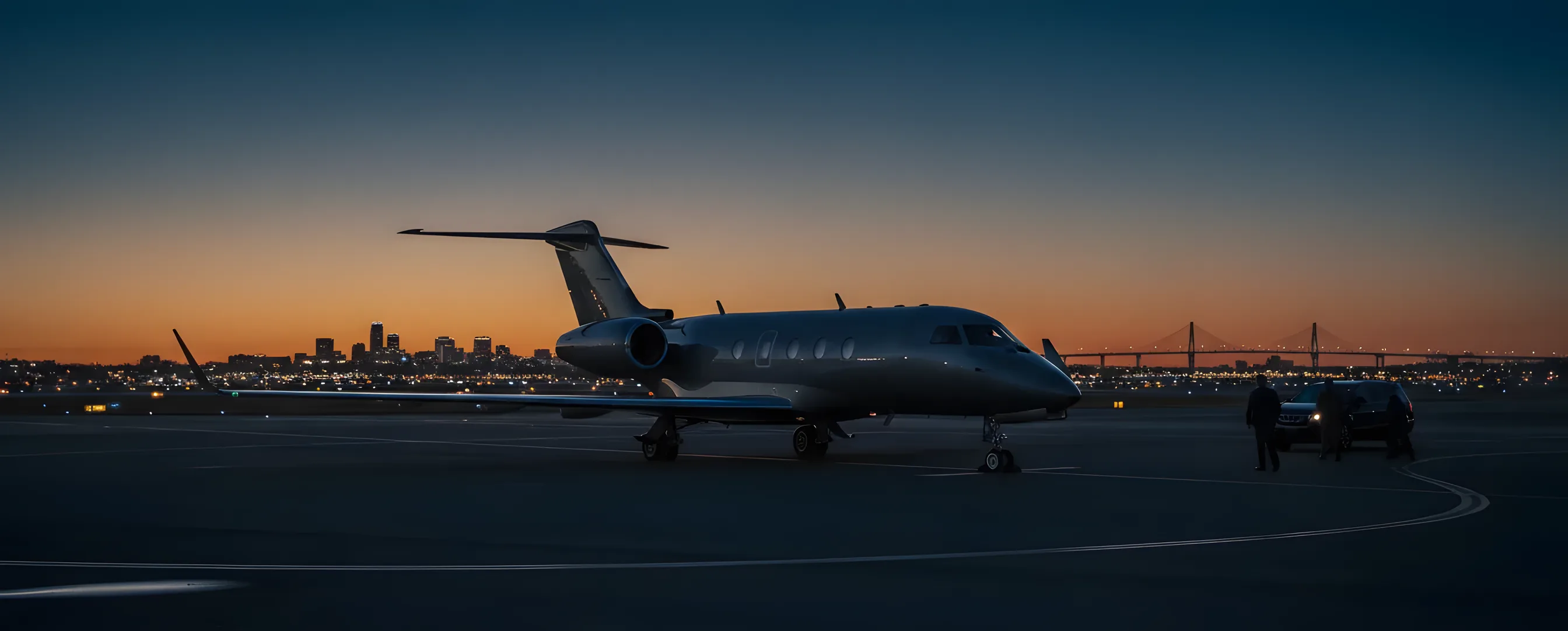 A private jet on an airfield at dusk, with the Sacramento city skyline glowing in the background.