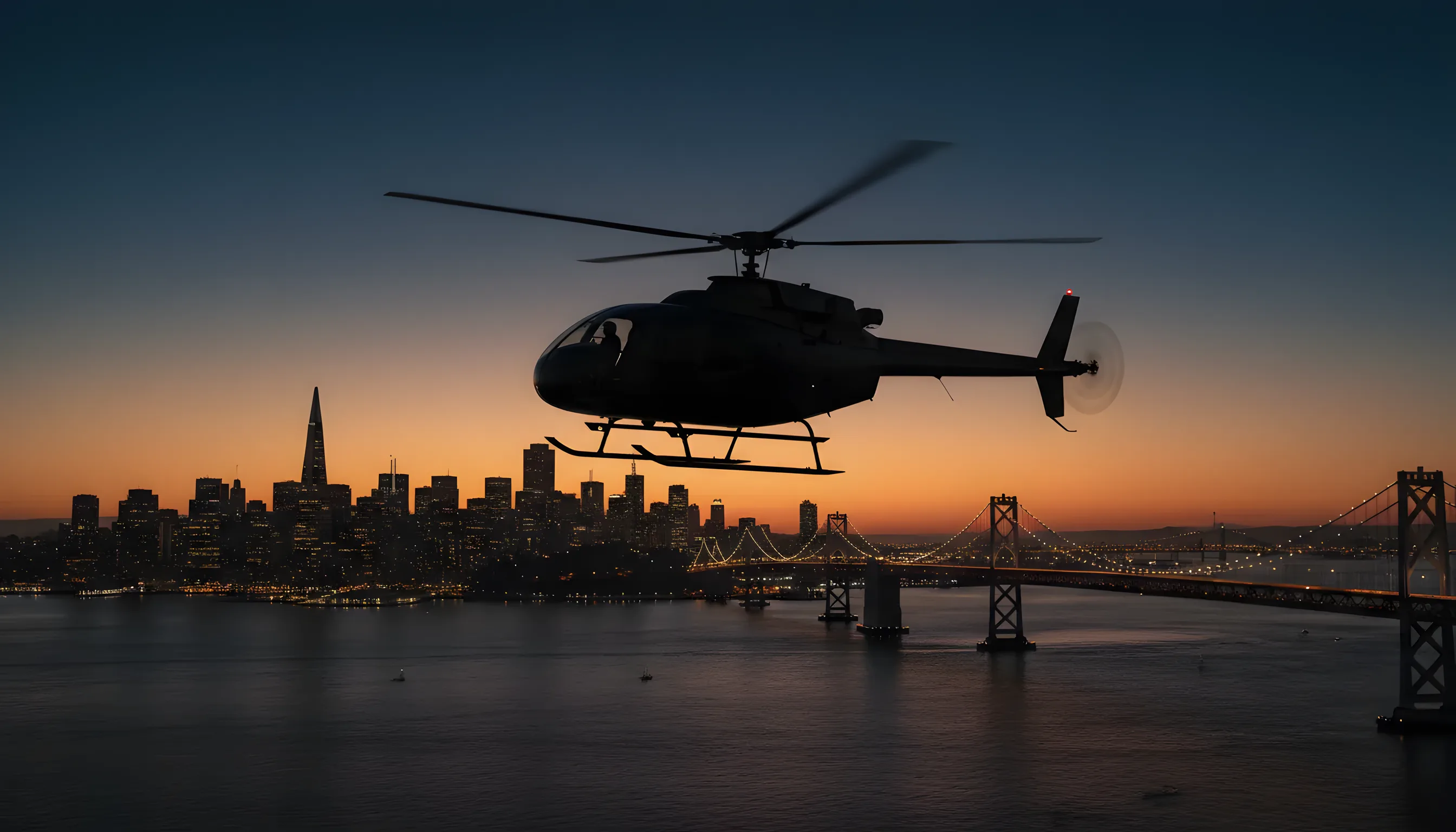 A helicopter flies over the San Francisco Bay at dusk, with the illuminated city skyline in the background.