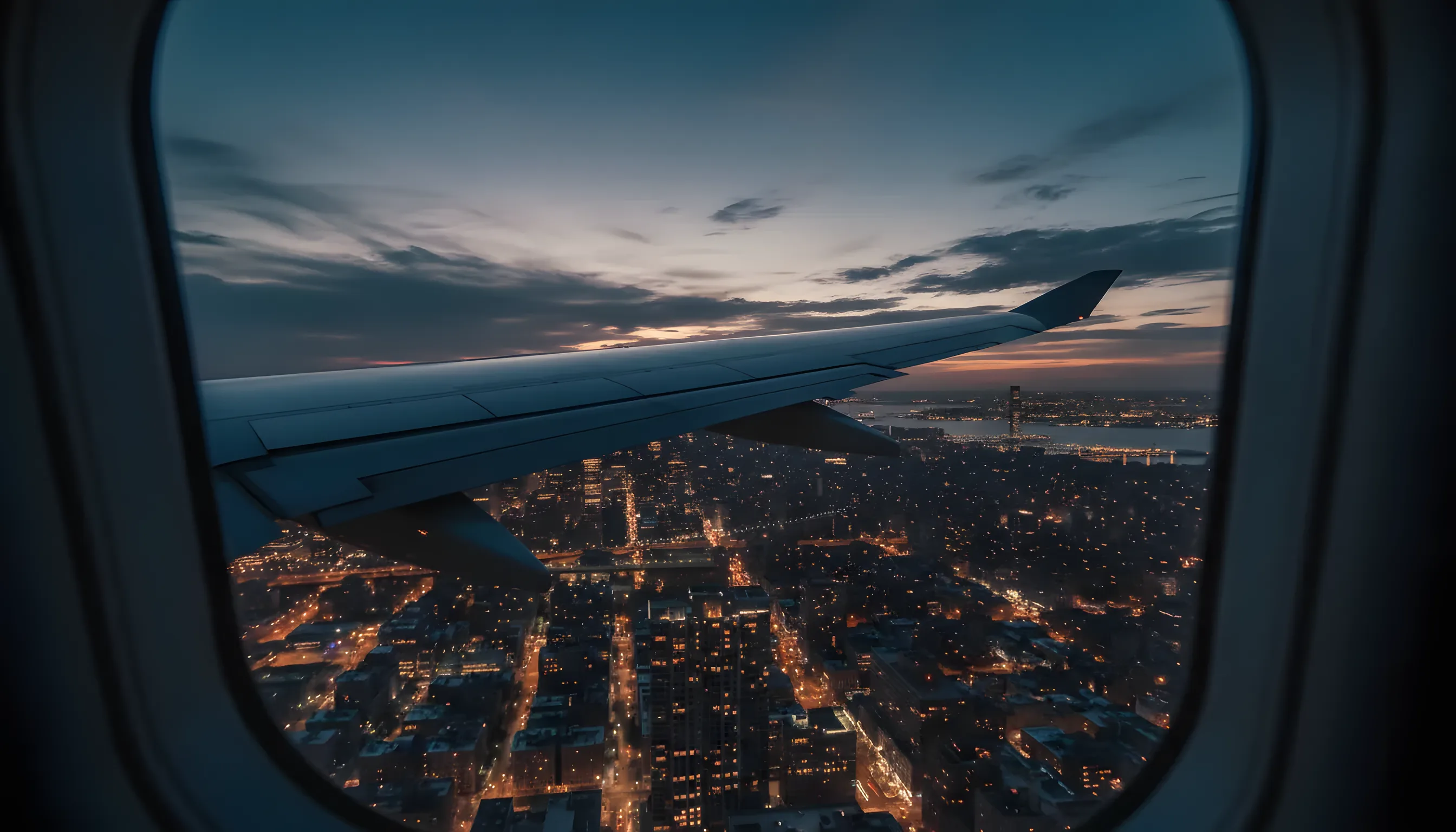 View of the New York City skyline at dusk from an airplane window.