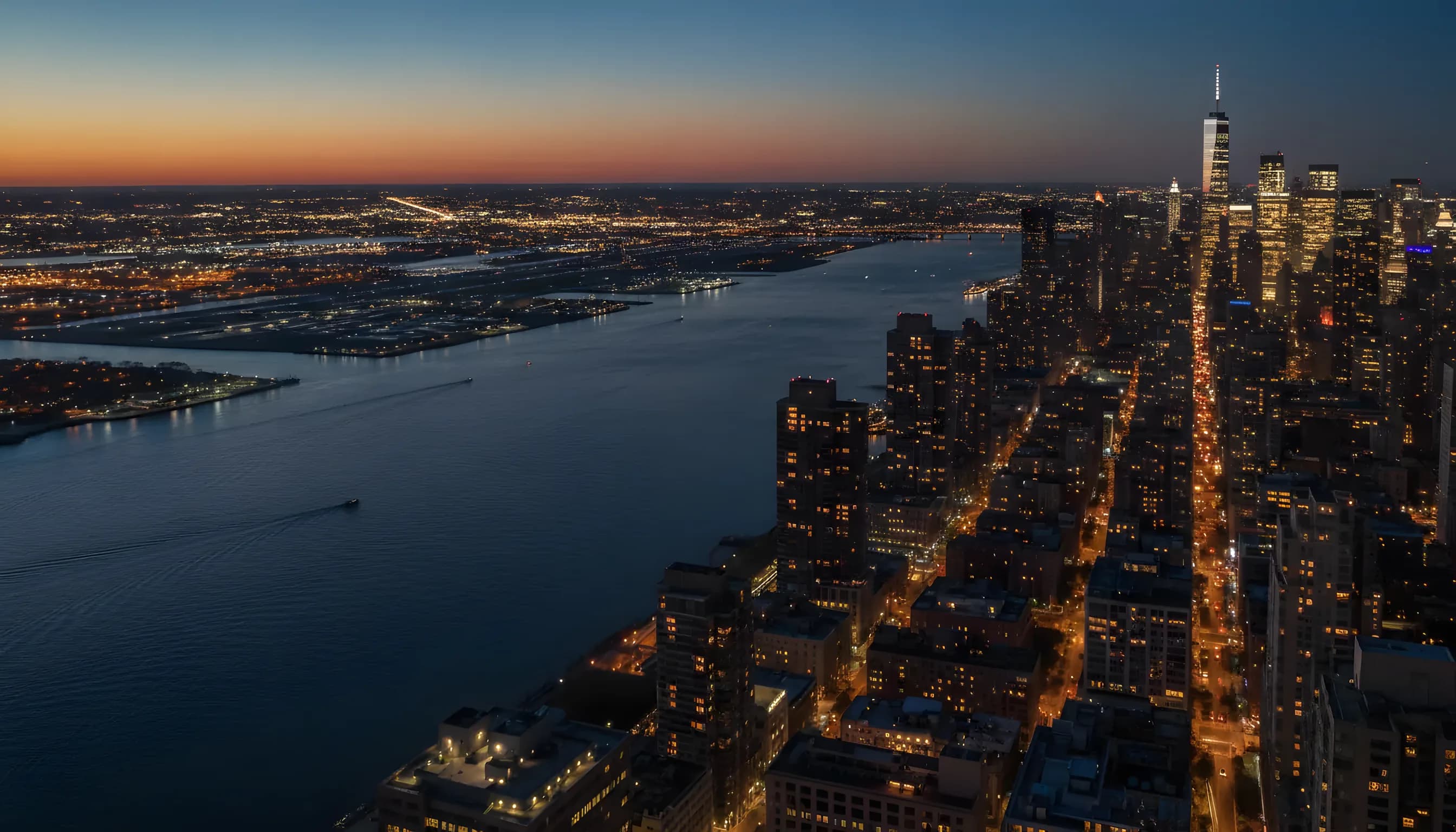 Aerial view of the Manhattan and New Jersey skylines at twilight, with an airport visible in the distance.