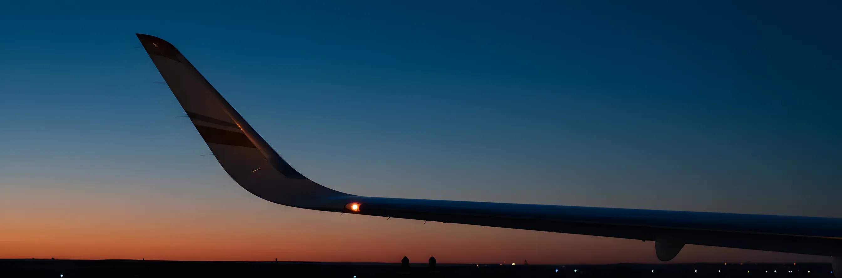 Close-up of a private jet's white winglet against a clear blue sky.