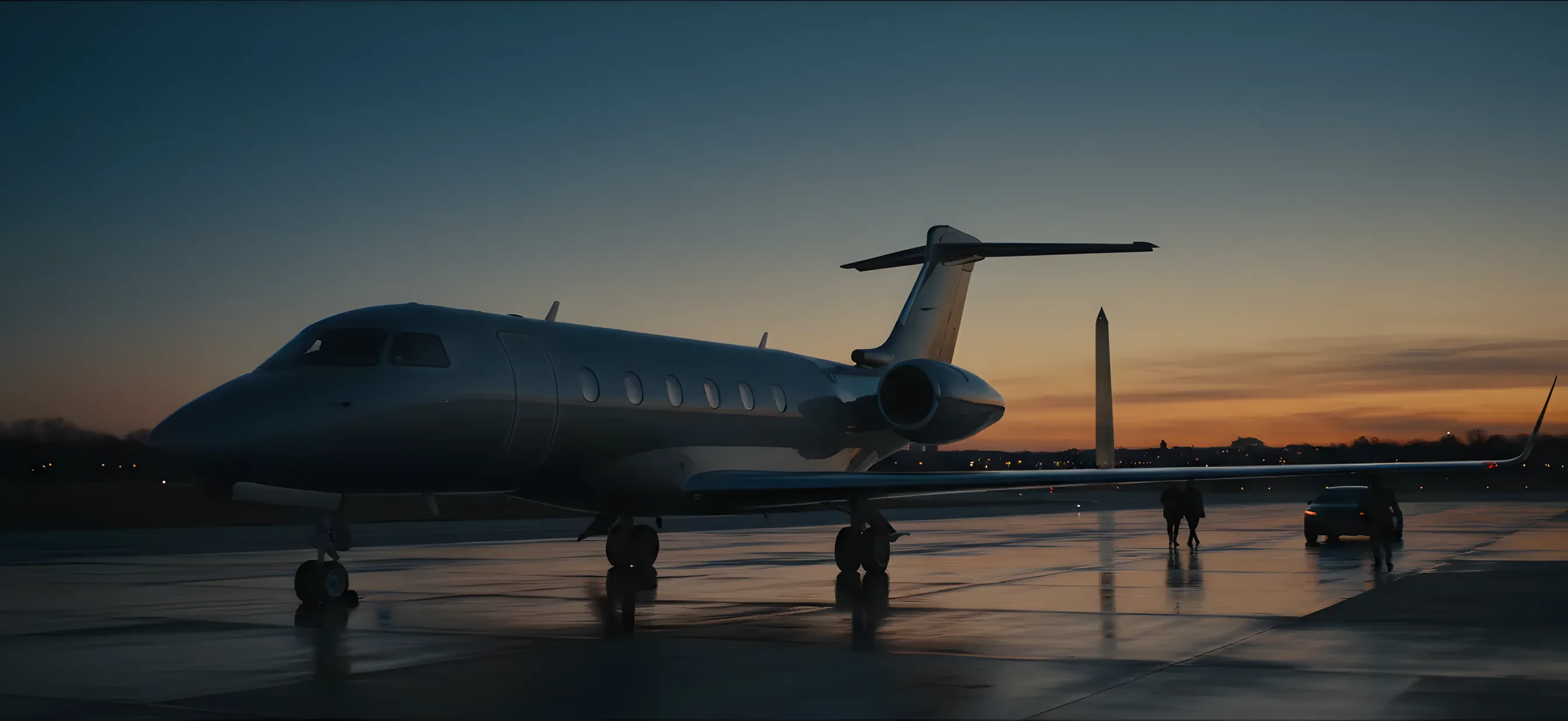 A private jet on an airfield with the Washington Monument visible in the distance at twilight.